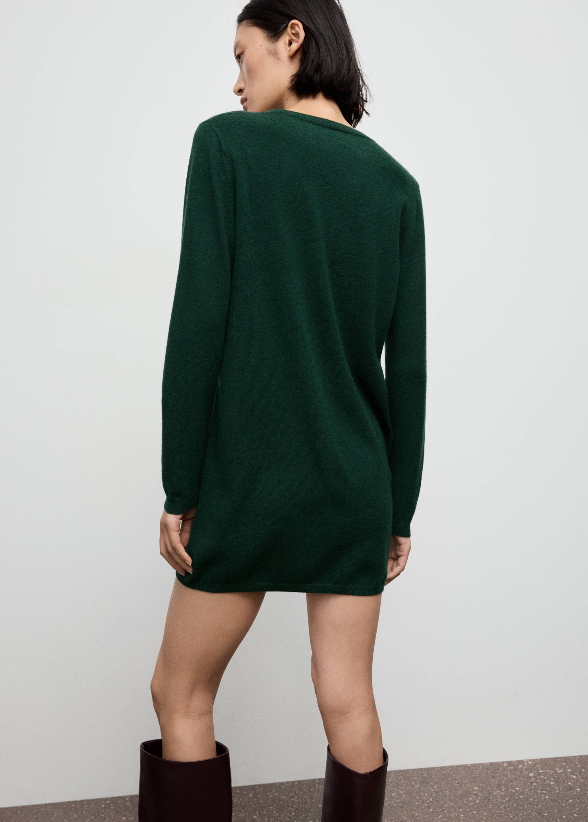 Vestido corto de punto en verde oscuro con manga larga, visto de espaldas.