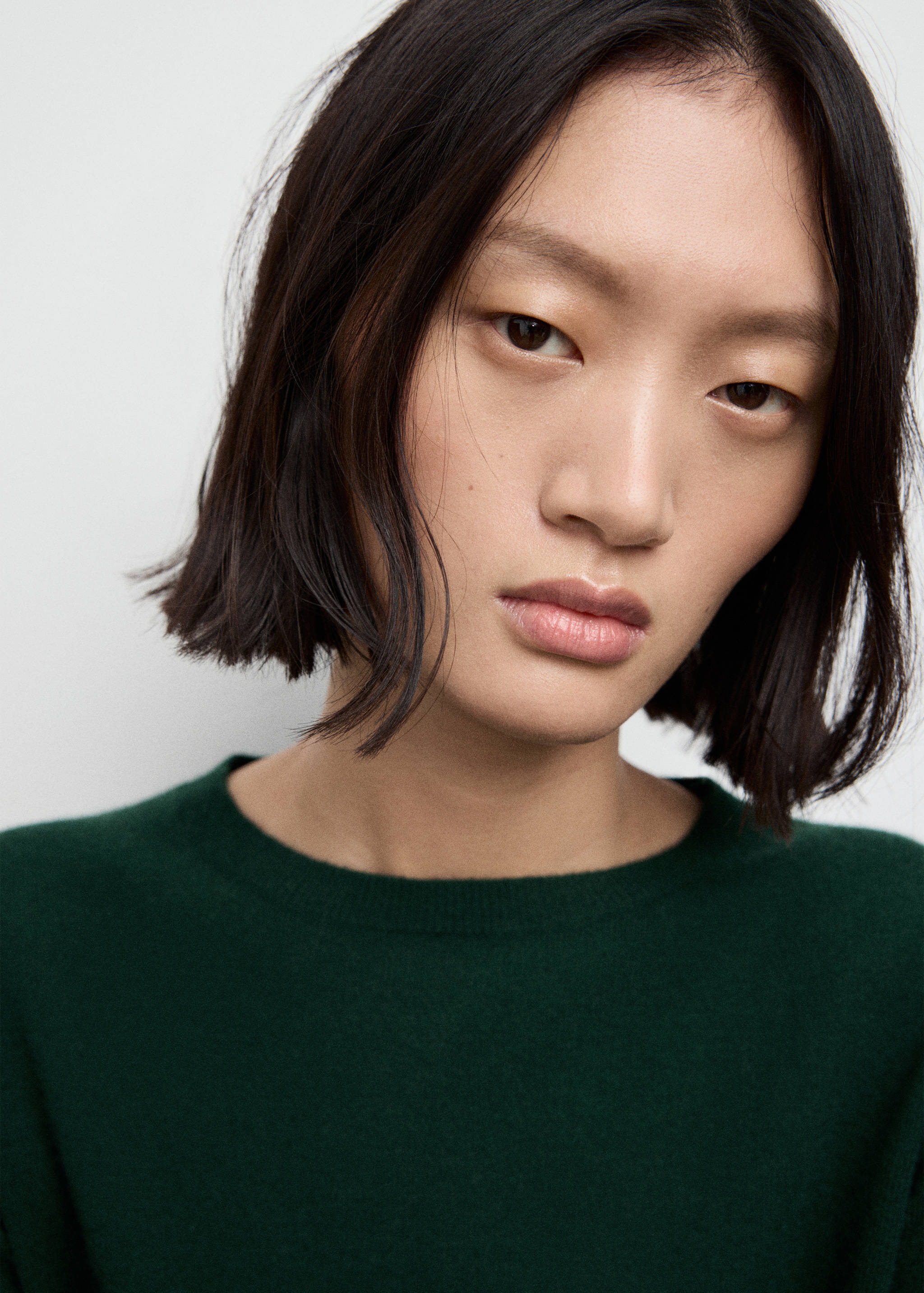 Detalle de vestido verde oscuro que muestra el cuello redondo y la cara de la modelo.