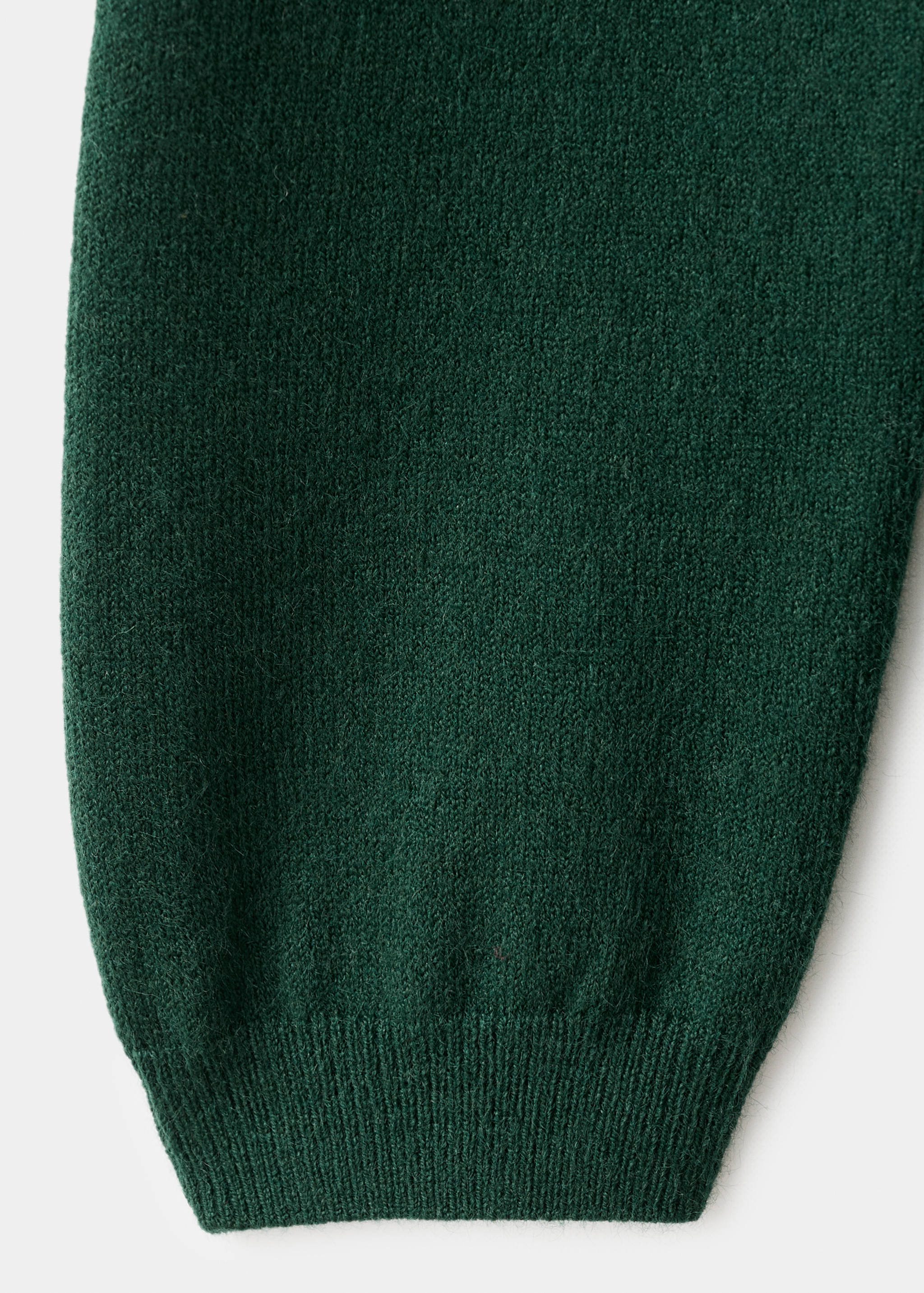 Detalle de la textura del tejido de punto en verde oscuro de un vestido.