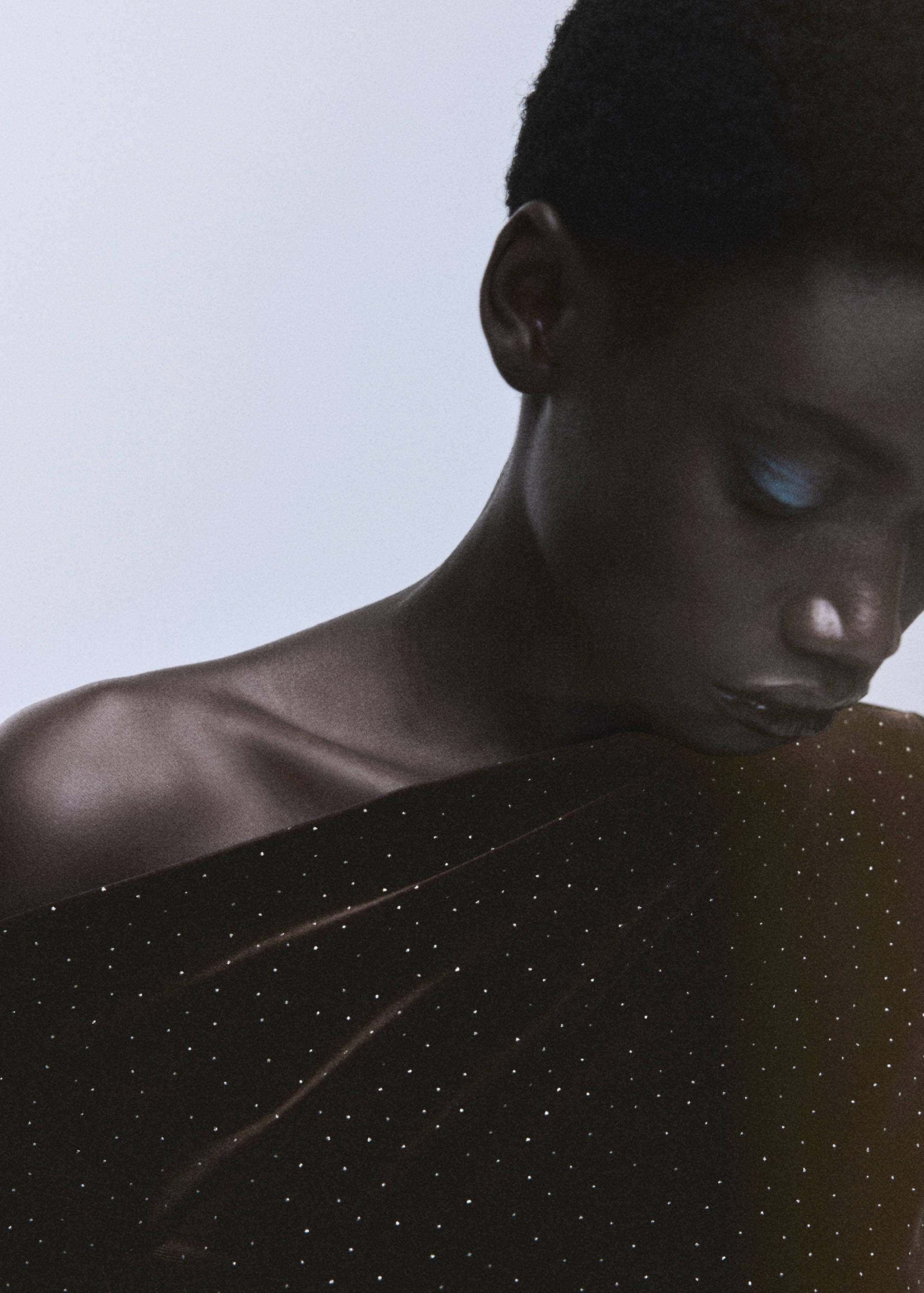 Close-up of a rhinestone-embellished velvet dress with an asymmetrical neckline.