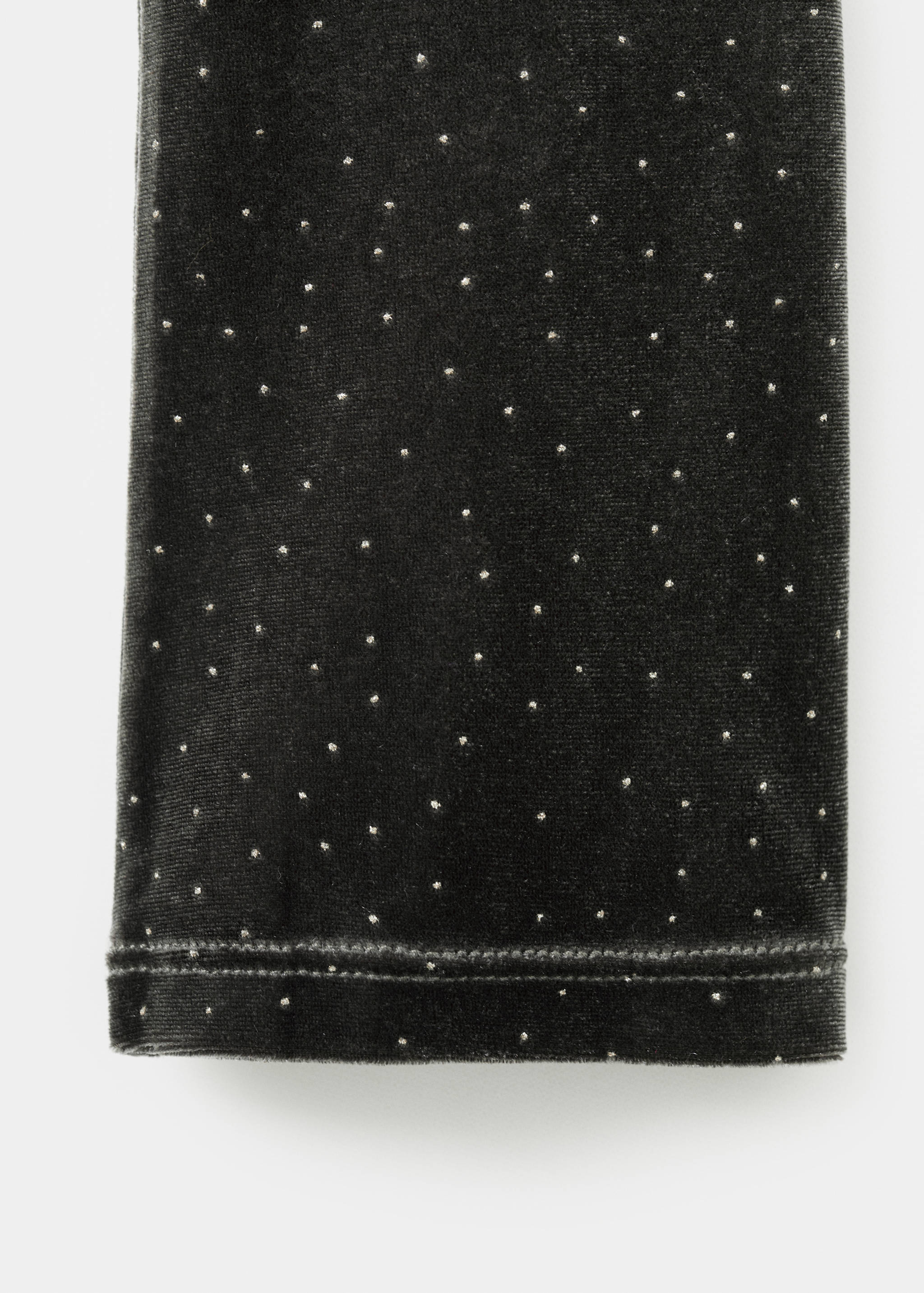 Close-up of a dark green velvet dress fabric with silver dots.
