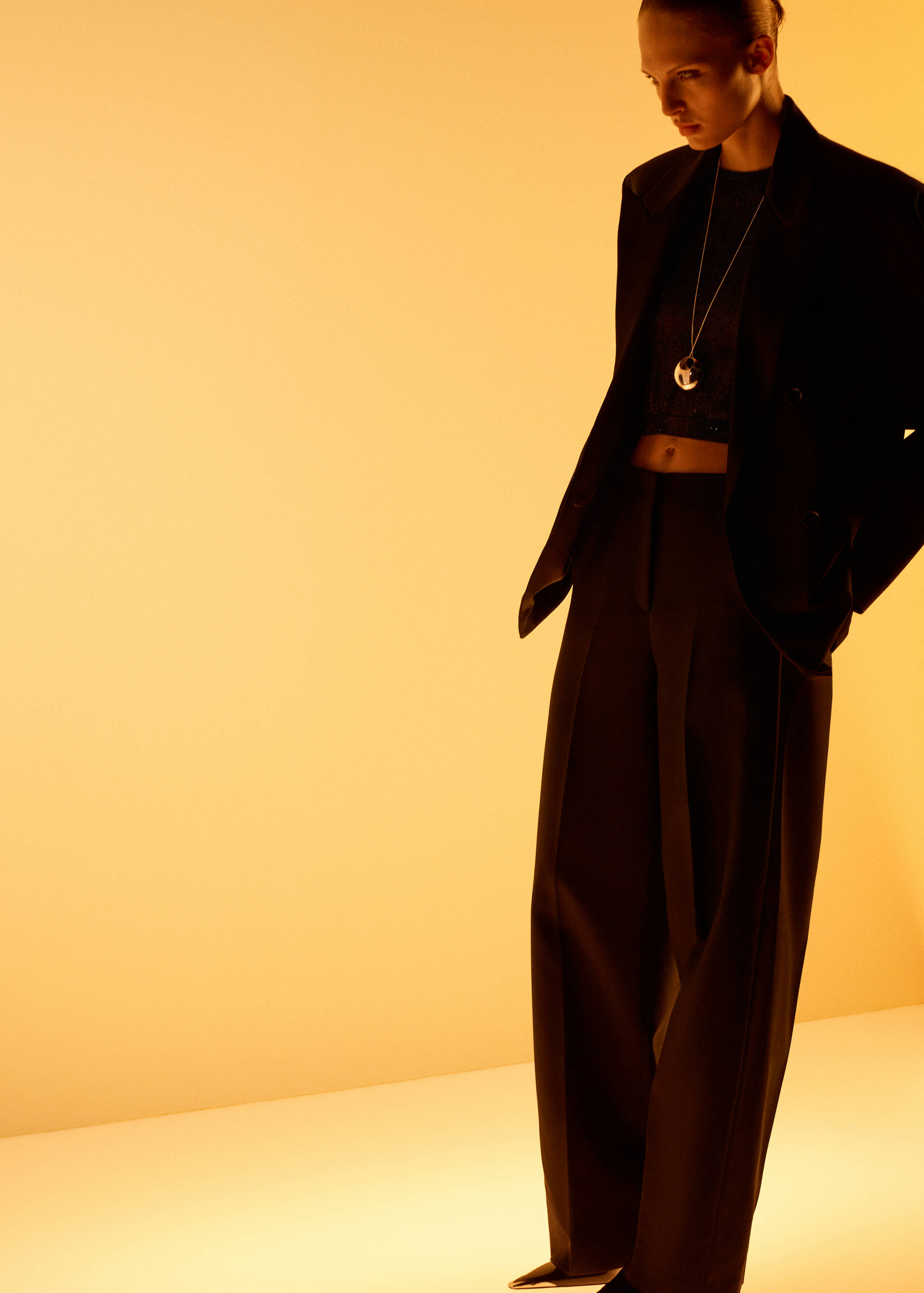 Black wide-leg trousers with pressed creases, worn with a black blazer and top.