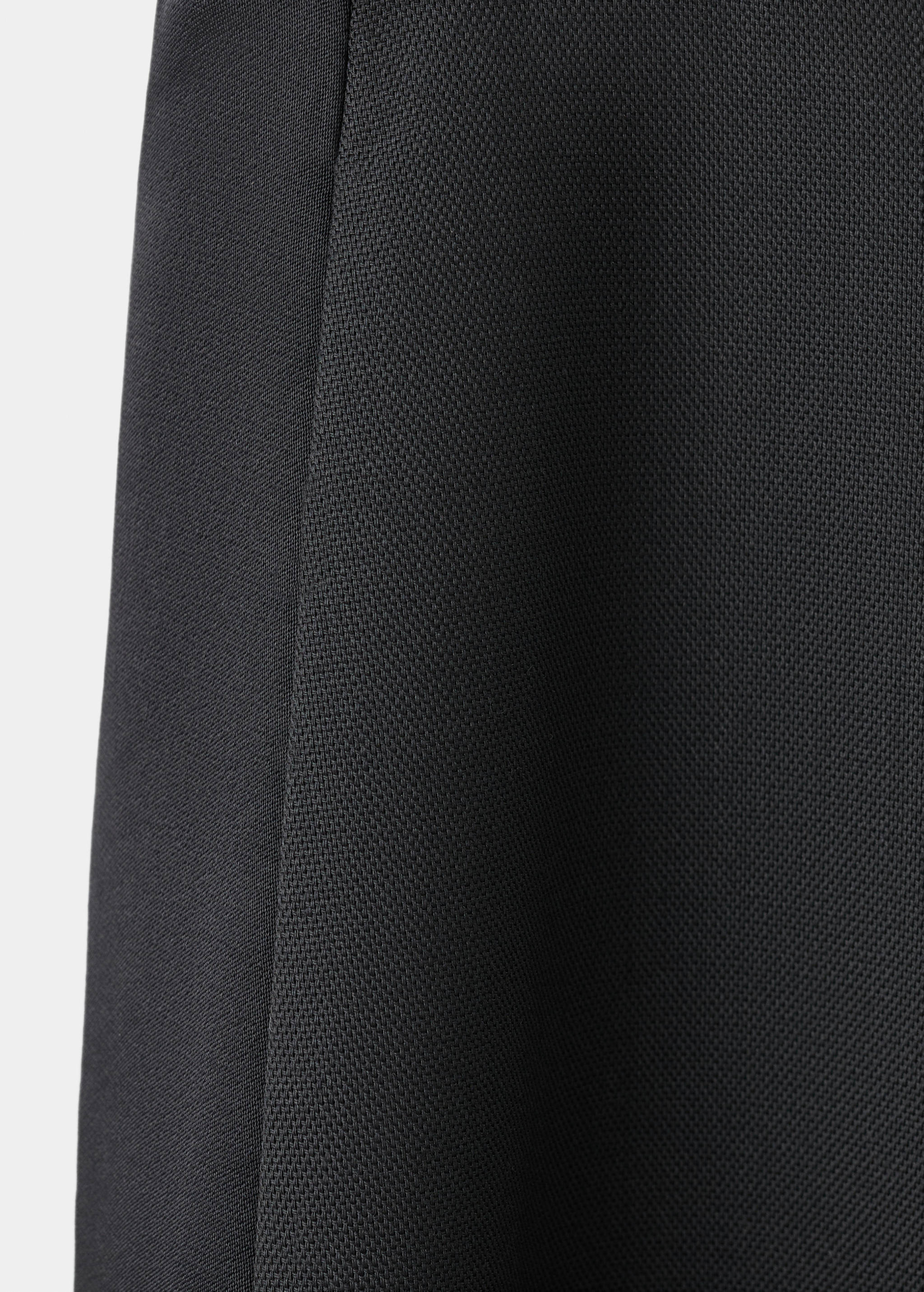 Close-up of black trousers featuring textured fabric and a smooth side stripe.