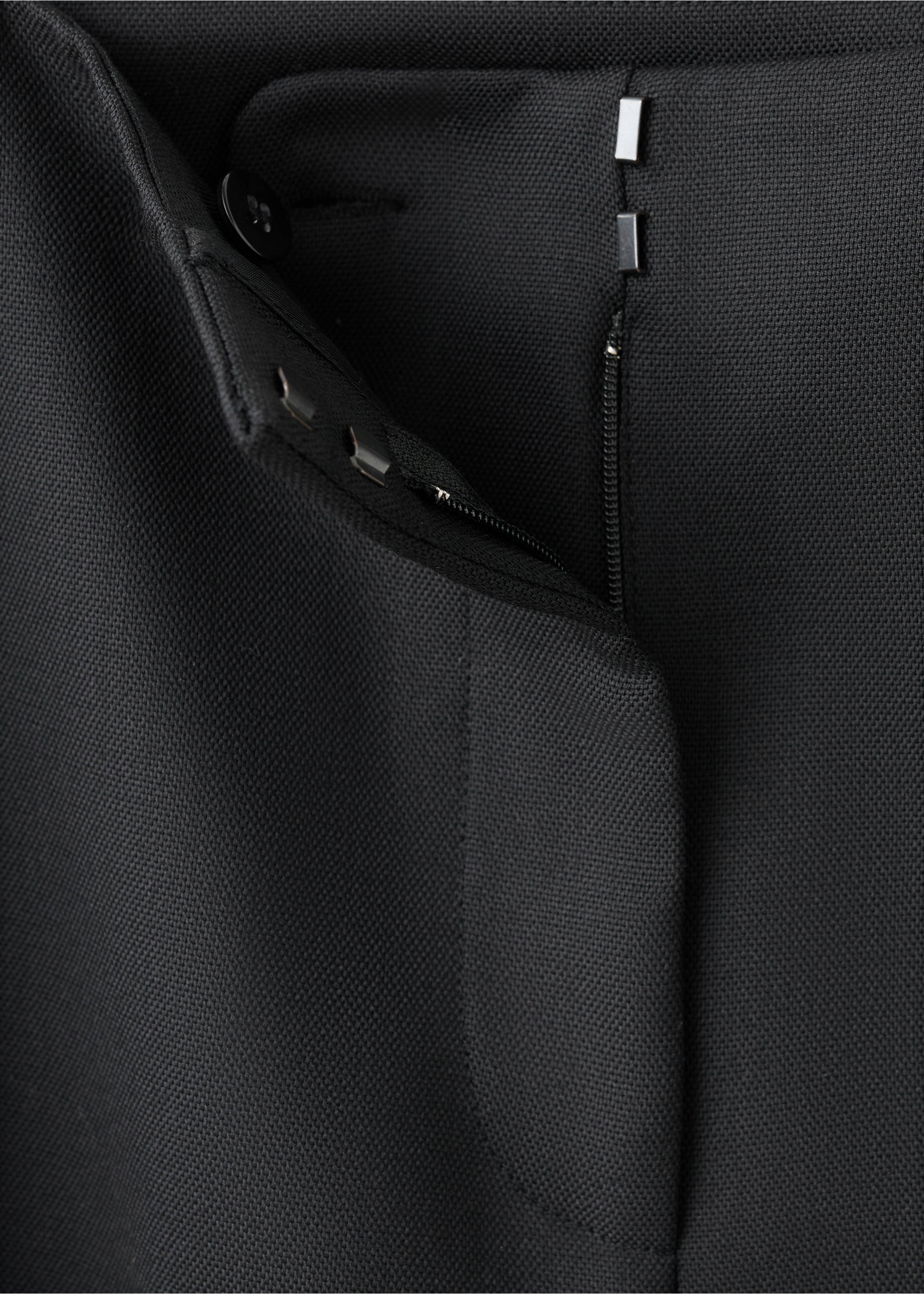 Close-up of black trousers showing the textured fabric and zip and hook-and-bar fastening., Black. Ref: 17049121-00.