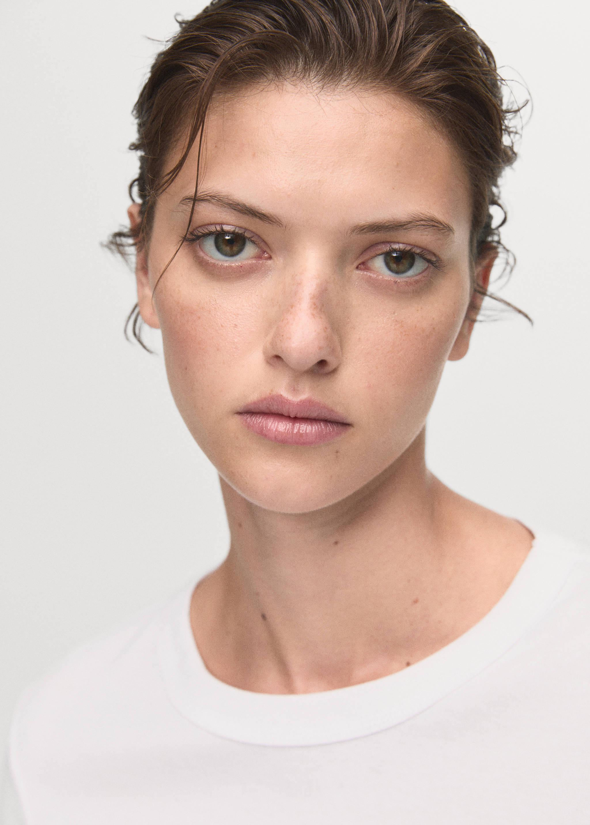 Close-up portrait of a model wearing a white crew-neck t-shirt.