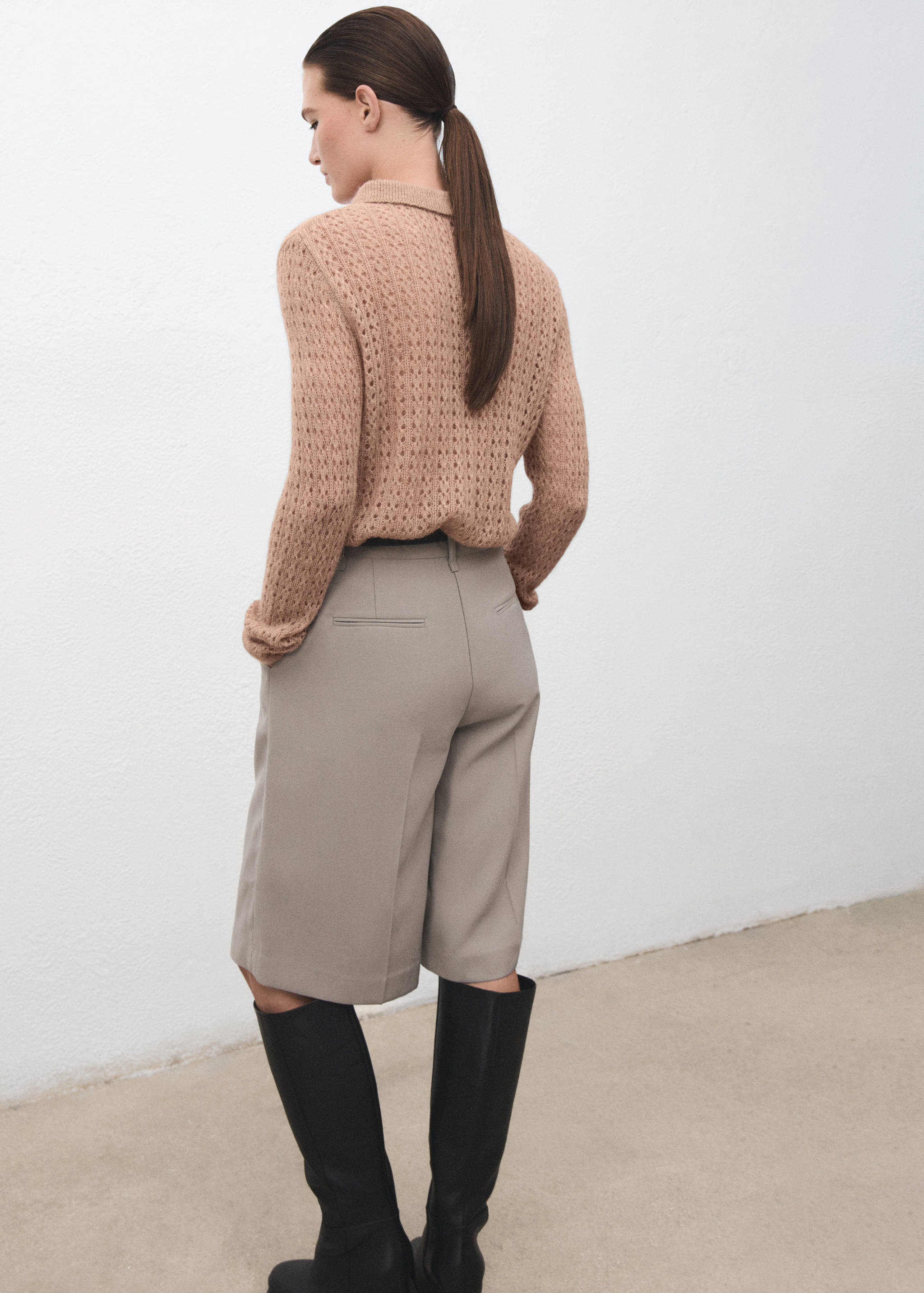Back view of a light brown knitted polo with a textured pattern.