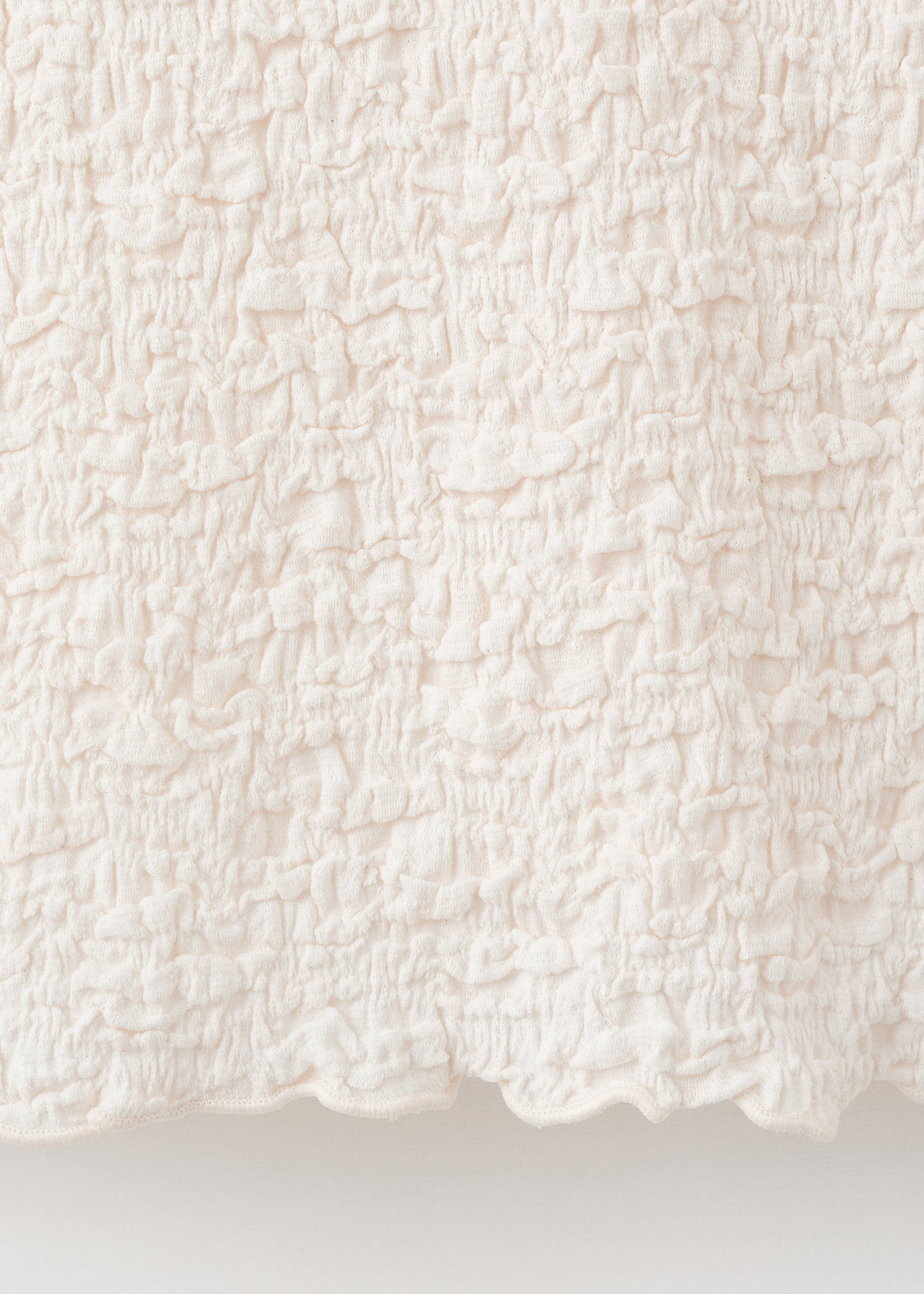 Close-up of the off-white textured crinkled fabric on a top