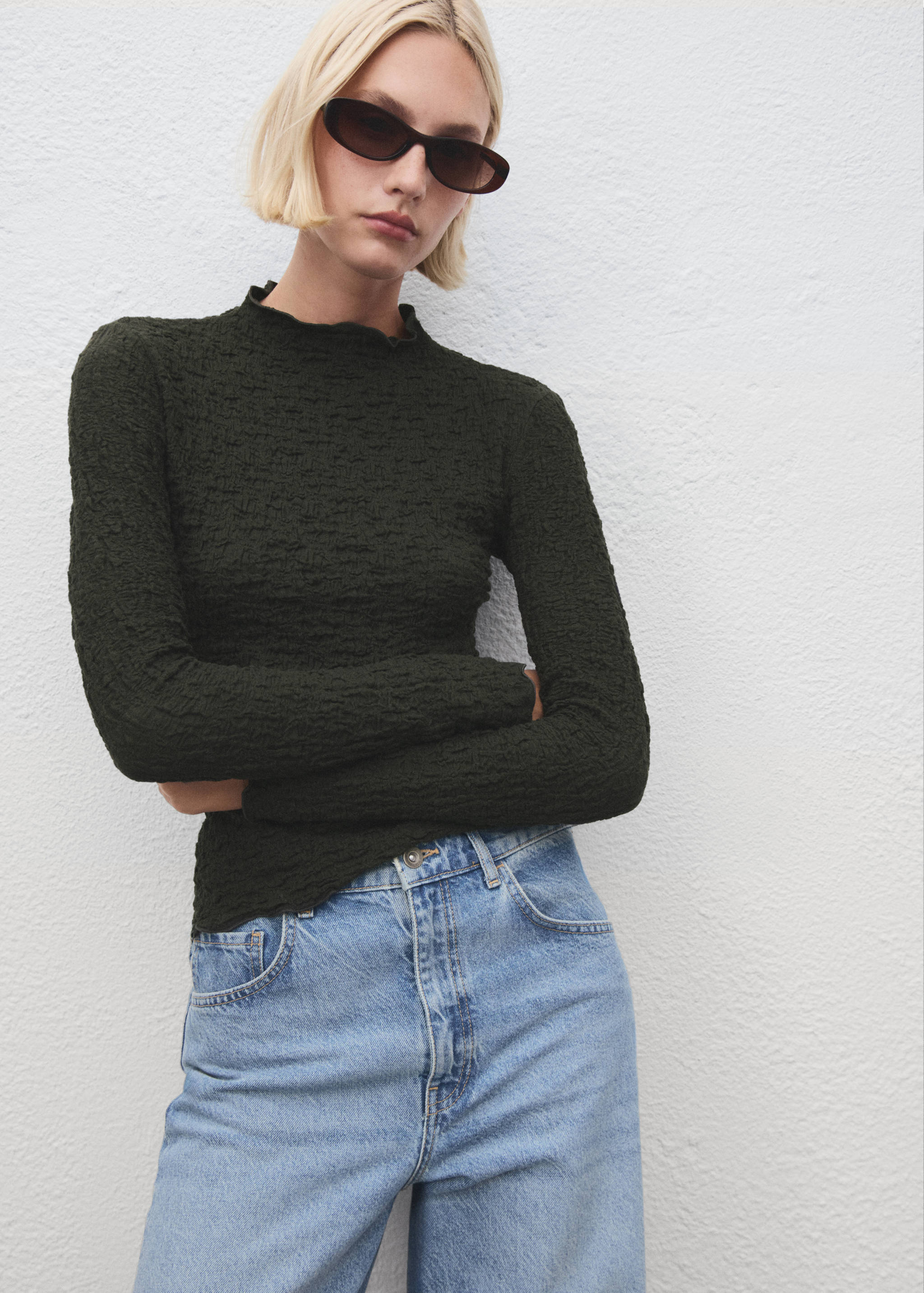 Dark green textured long-sleeve top with mock neck and lettuce edges.