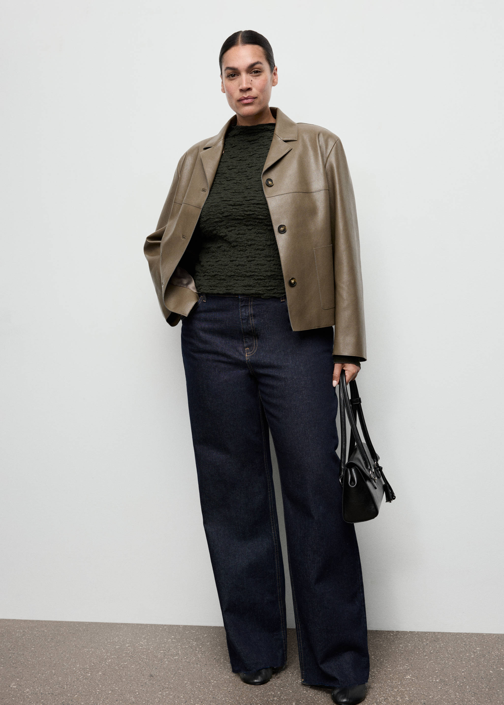 Dark green textured top worn with an olive green jacket and dark blue trousers