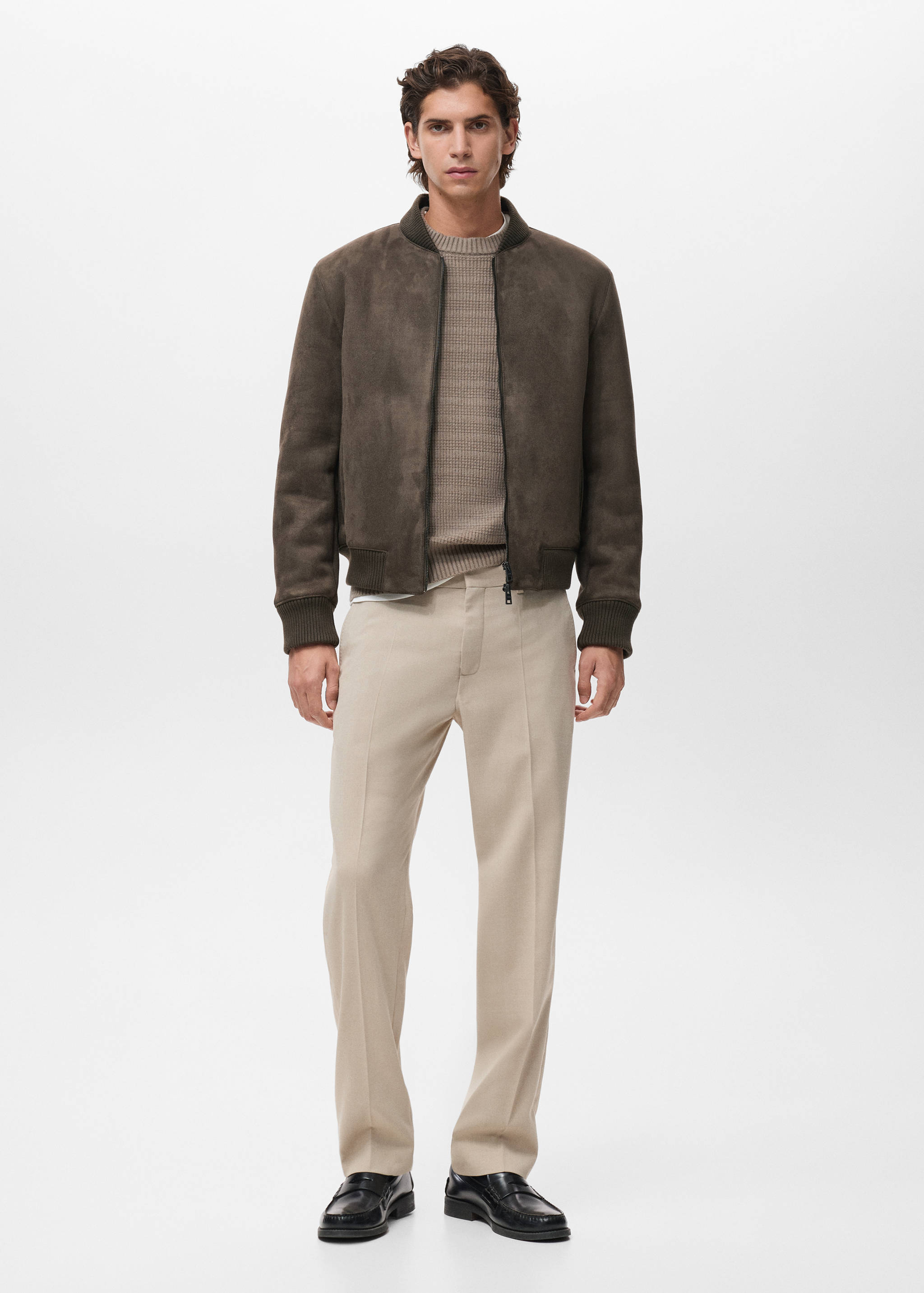 Dark brown suede bomber jacket with ribbed knit trims, worn with a beige jumper and trousers.