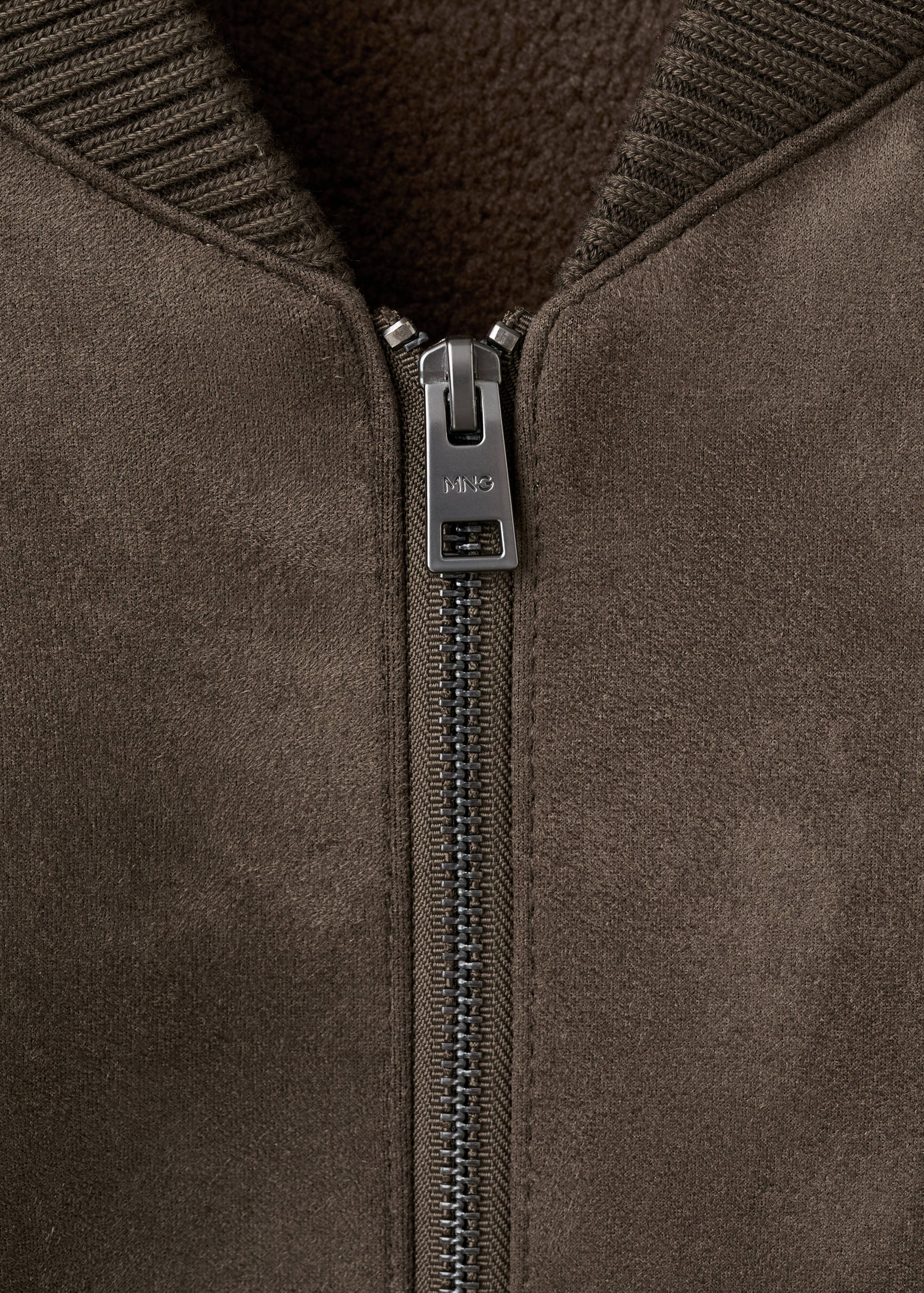Close-up of a brown jacket featuring a zip fastening and ribbed collar.