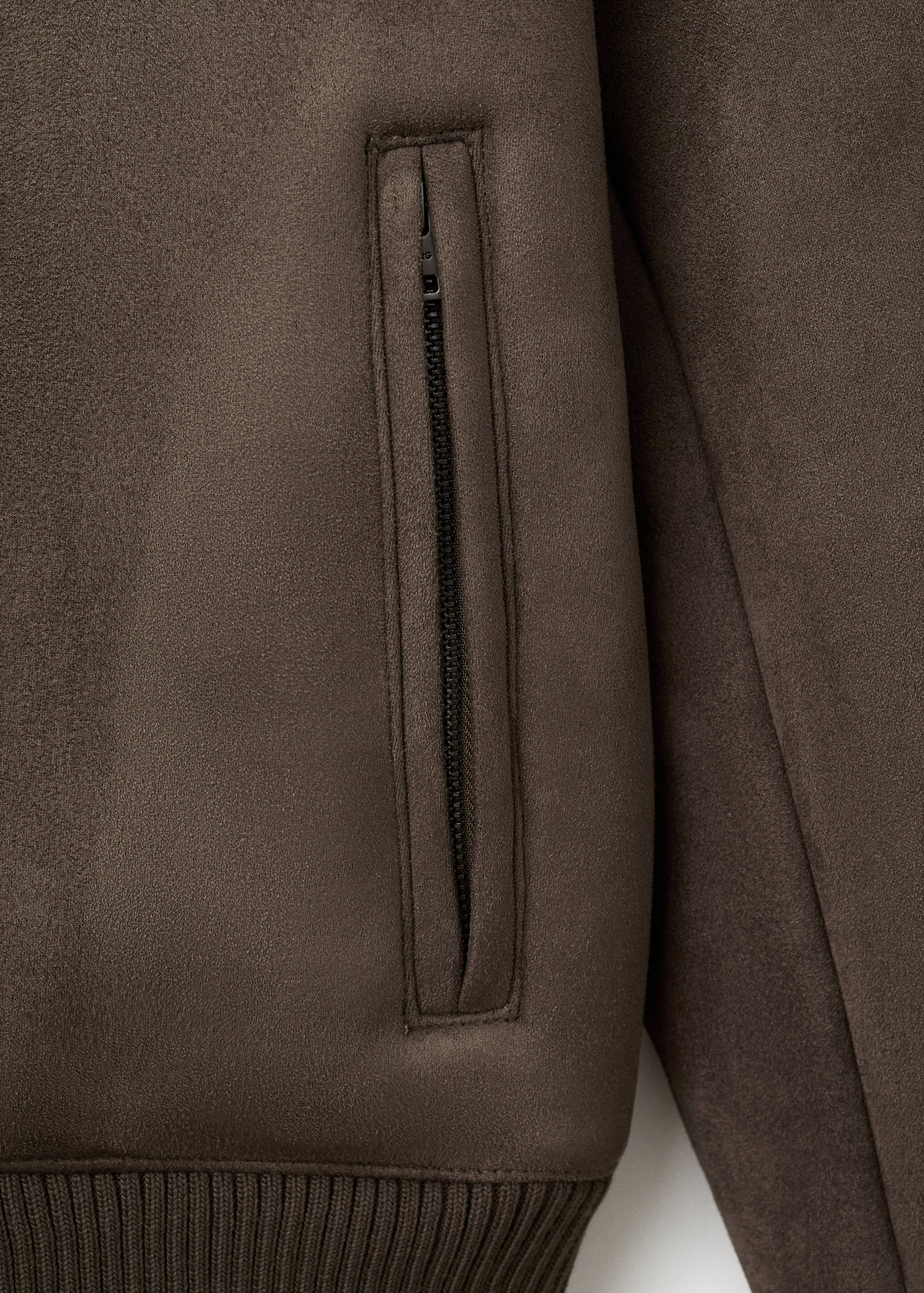 Close-up of a dark brown jacket showing the fabric texture and a zipped pocket.