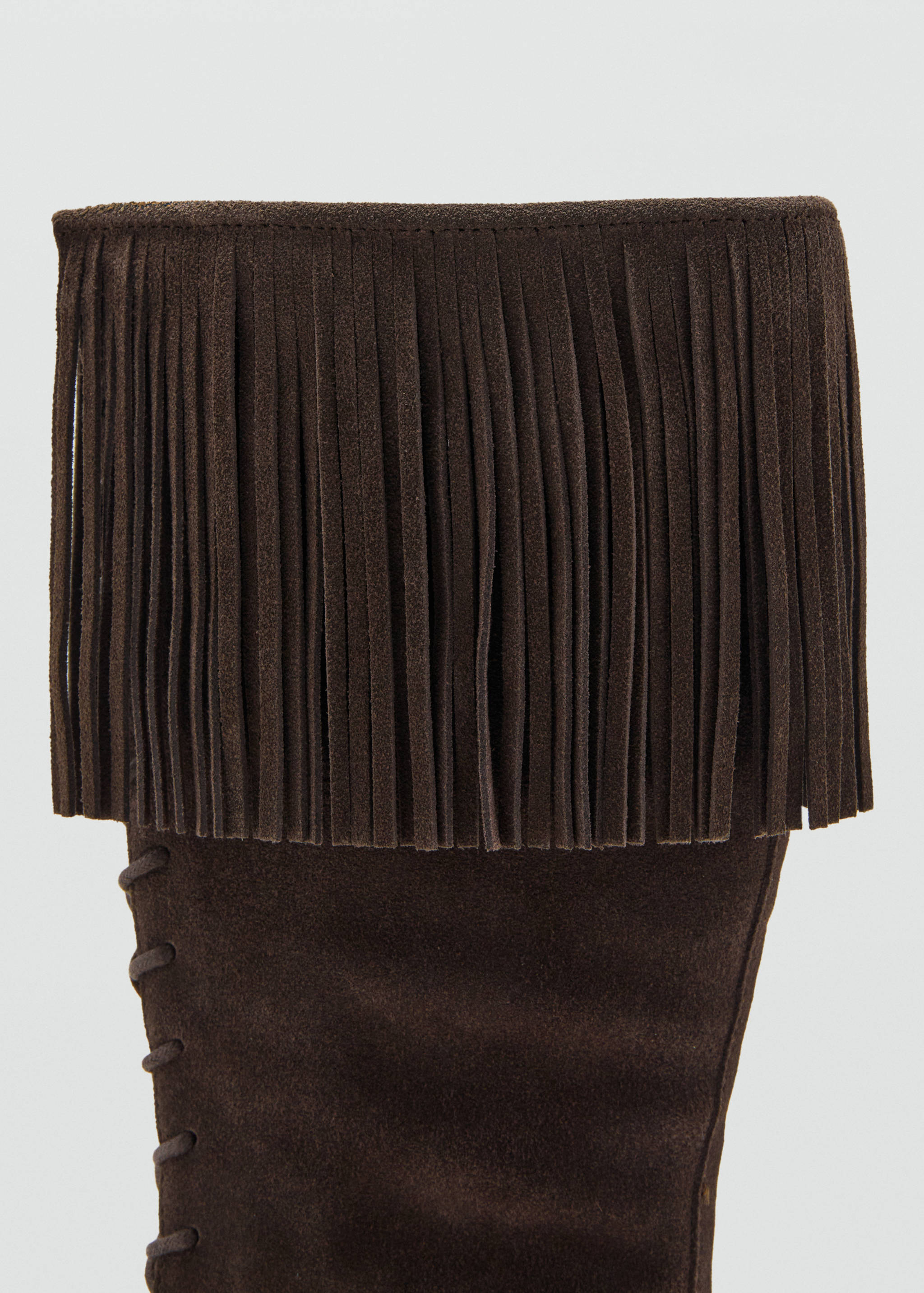 Dark brown suede boot detail featuring a fringe cuff and side lacing.