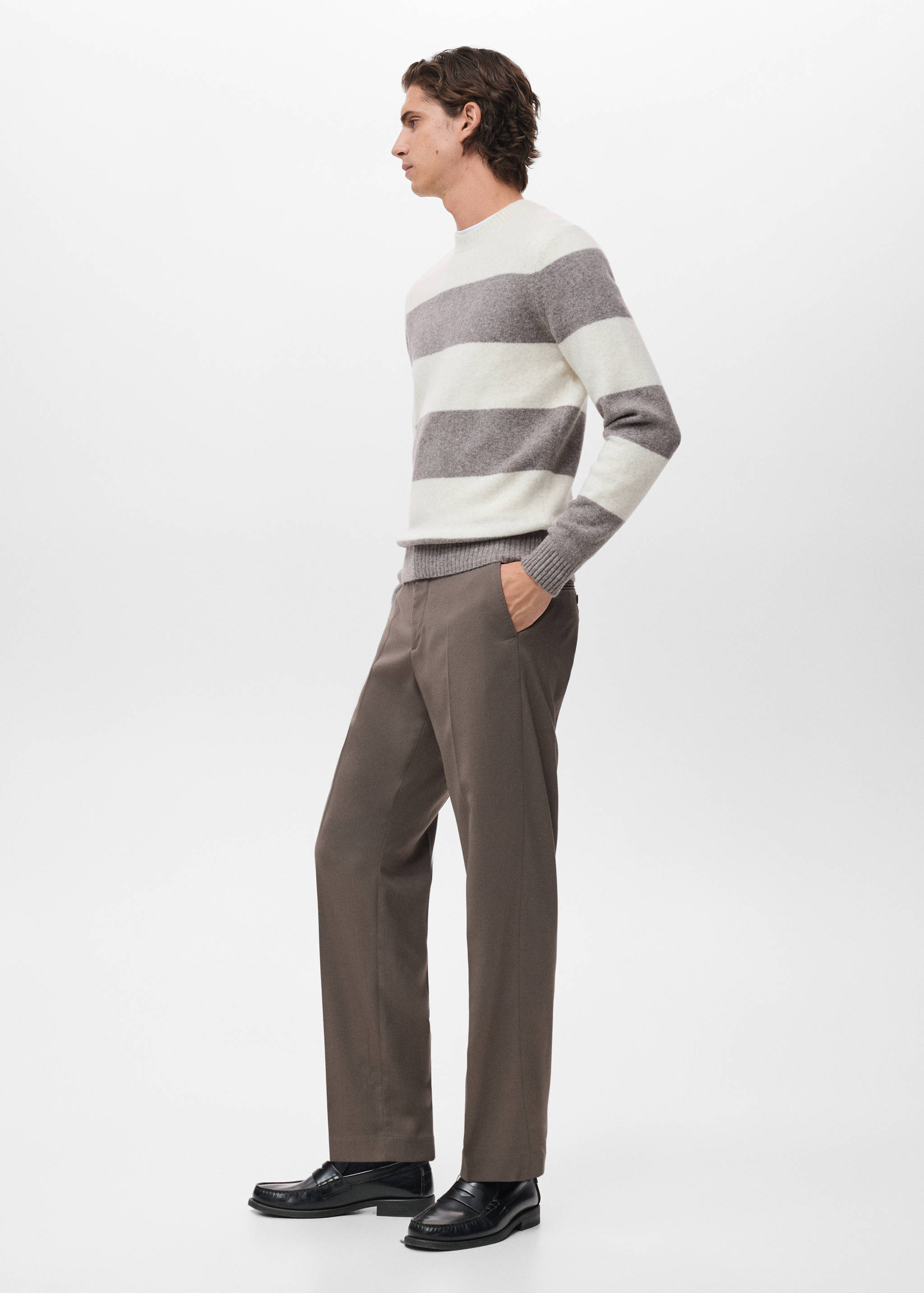 Off-white and grey striped crew neck jersey worn with trousers.