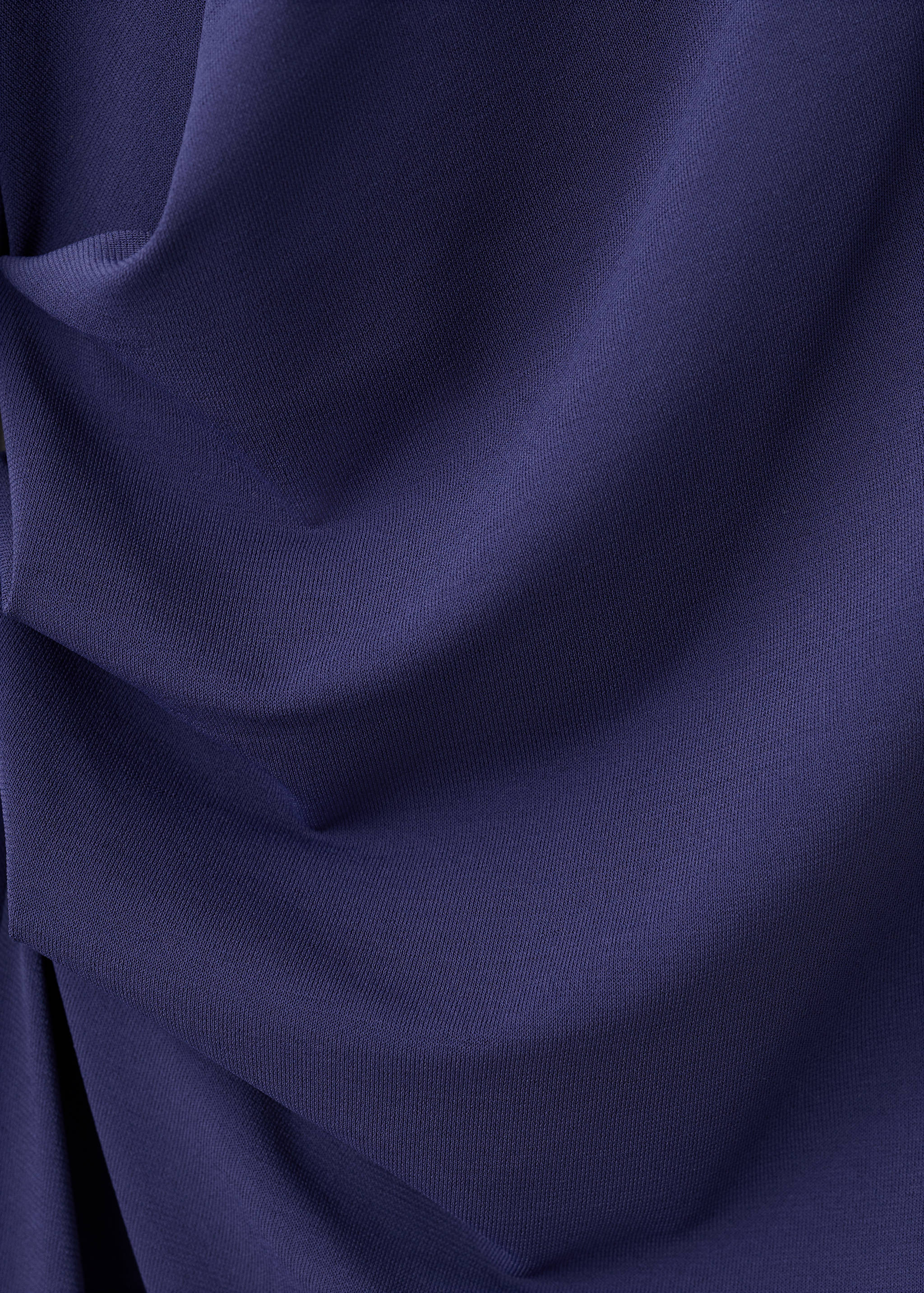 Close-up of the dark purple fabric and draping of a dress.