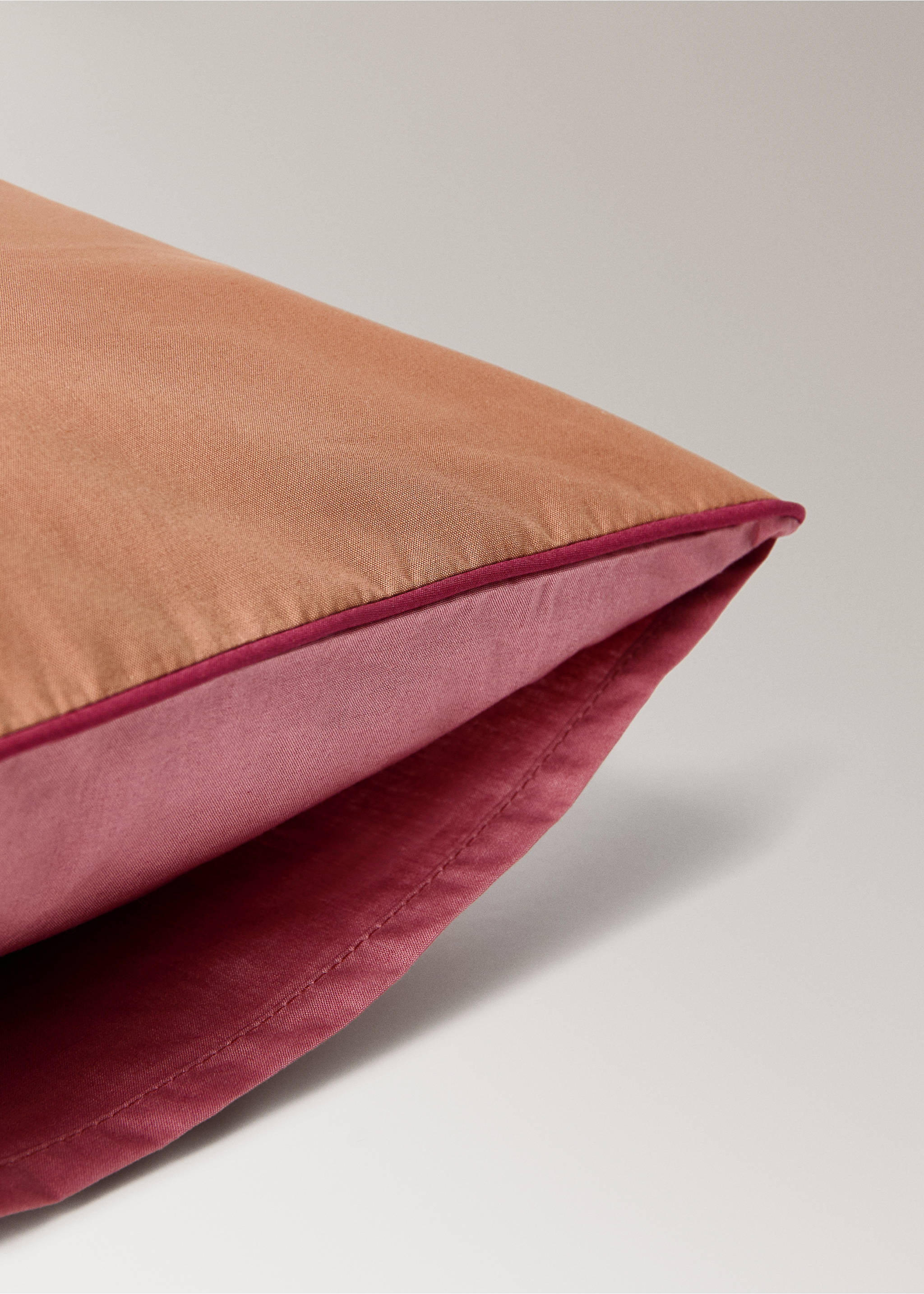 Close-up of a two-tone cot pillowcase in orange-brown and pink with piped trim., Pink. Ref: 17061545-00.