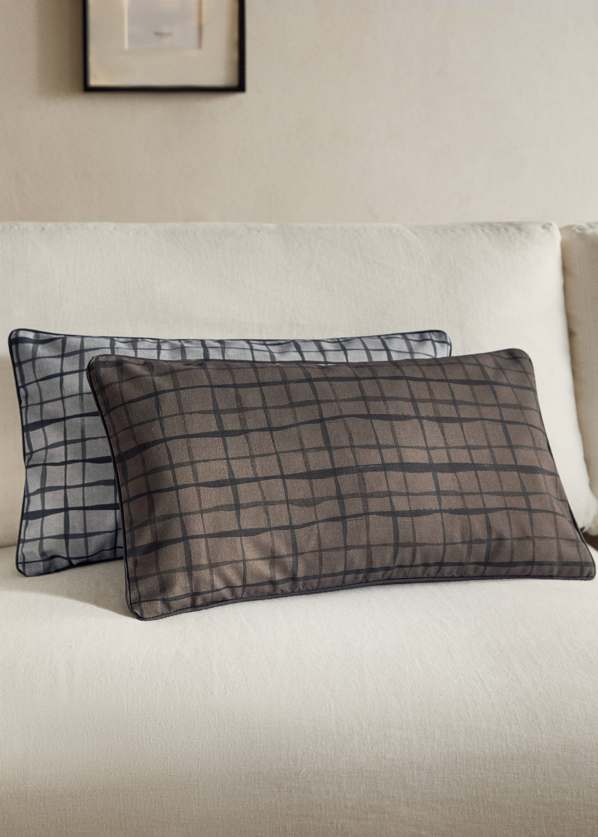 Brown rectangular cushion cover with a black painted check pattern on a sofa.