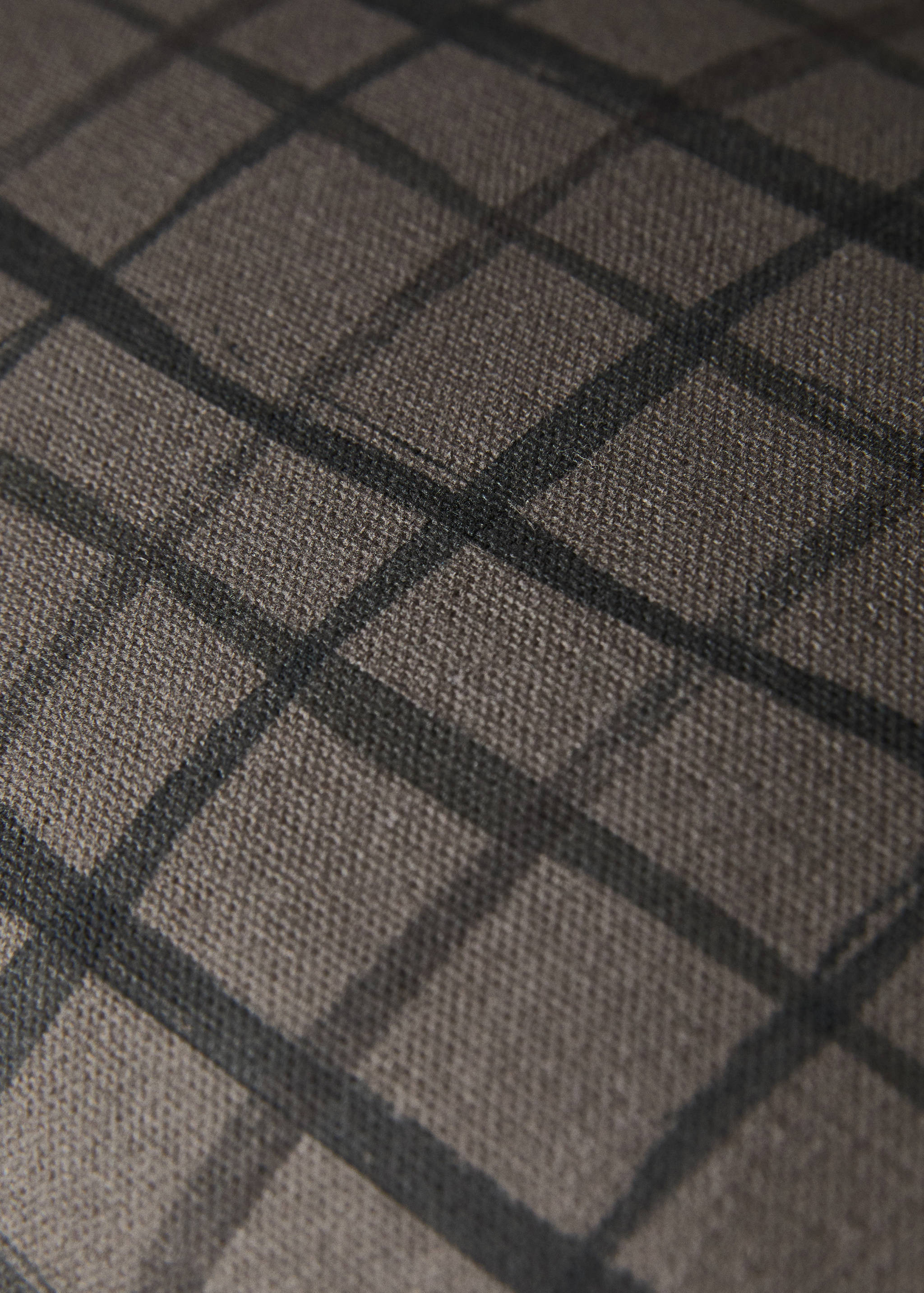 Close-up of a cushion cover with a dark checked pattern.