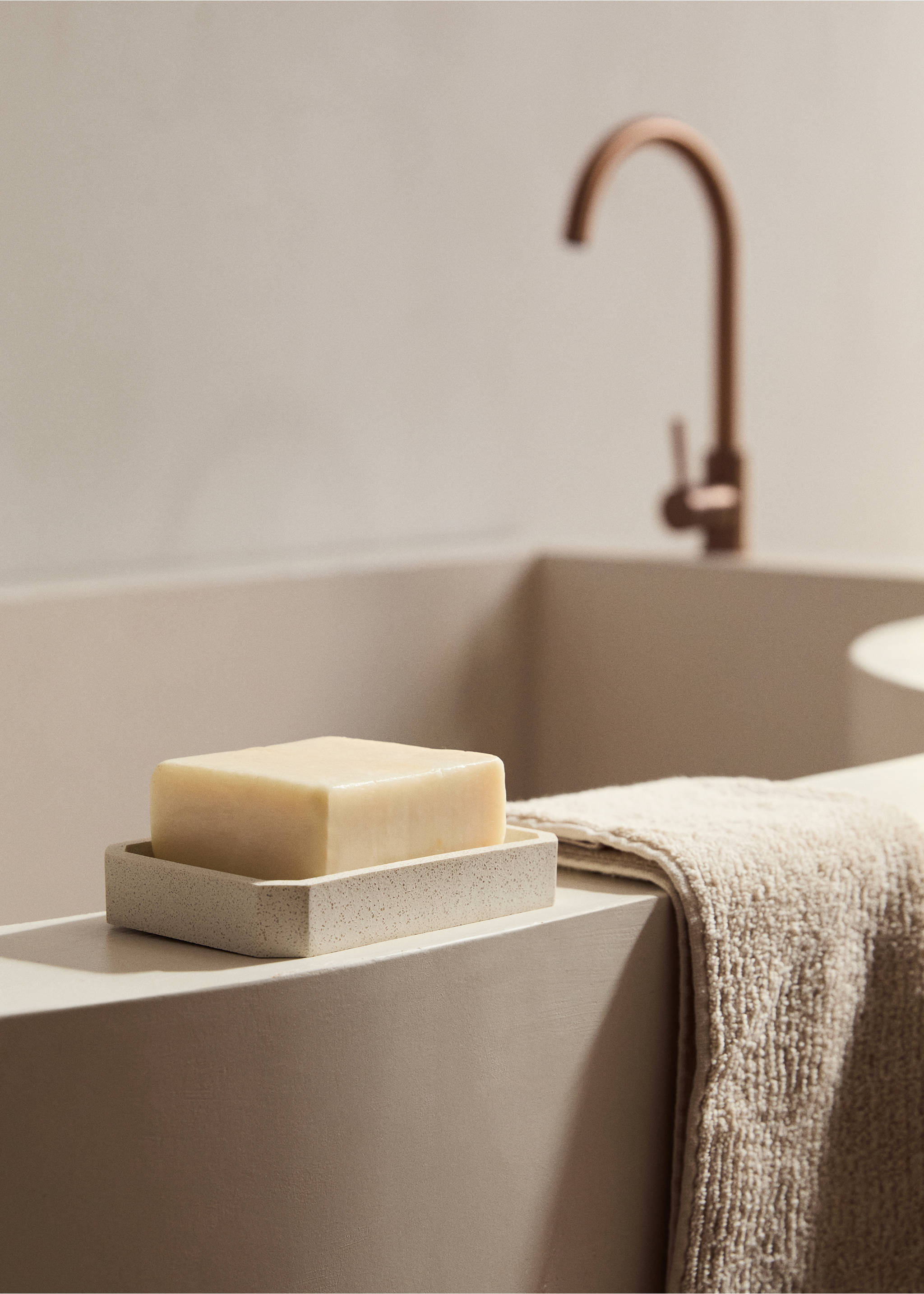 Beige speckled soap dish holding a bar of soap on a bathroom counter., Sand. Ref: 17062919-00.