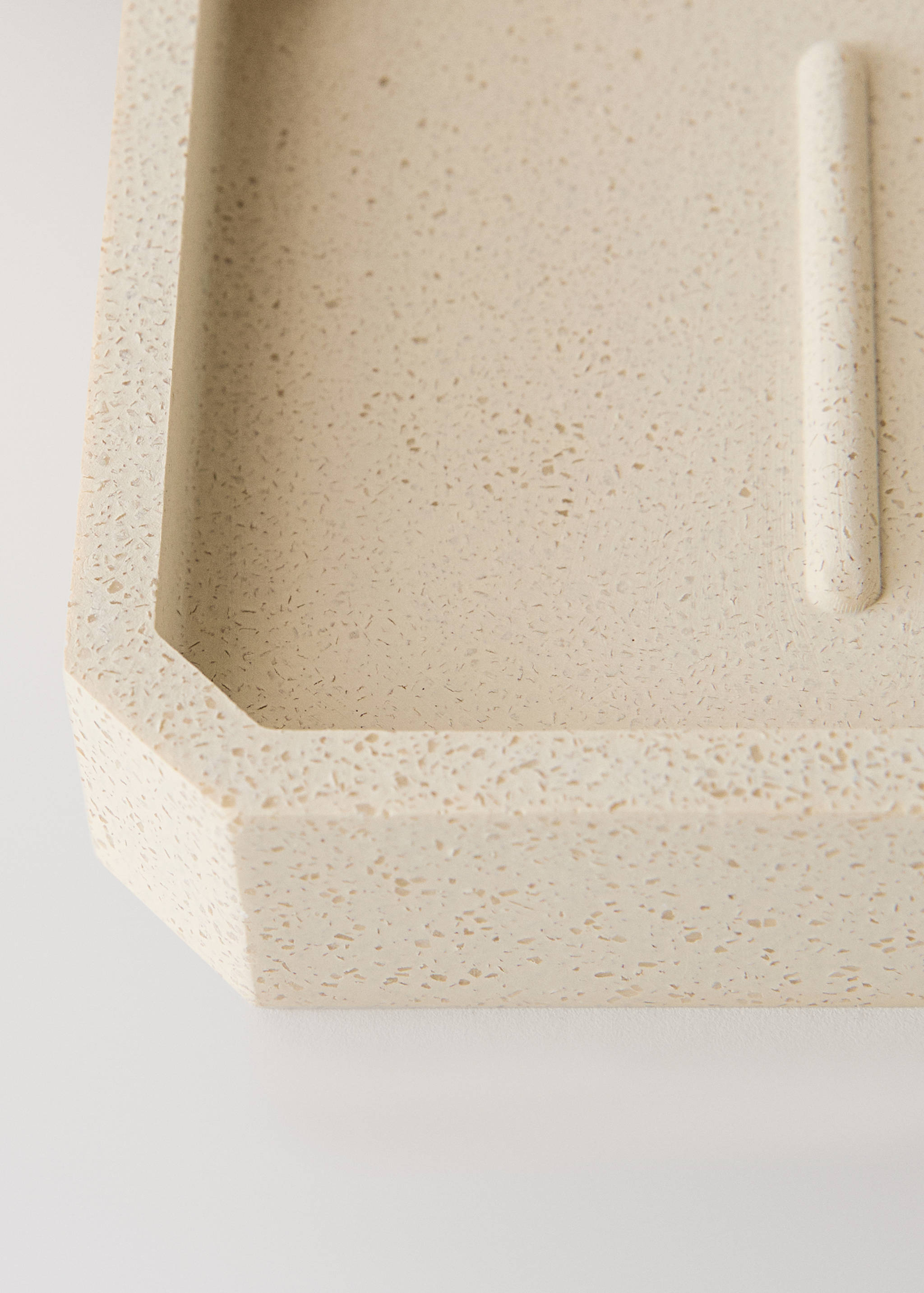 Close-up of a beige speckled soap dish with angled corners.