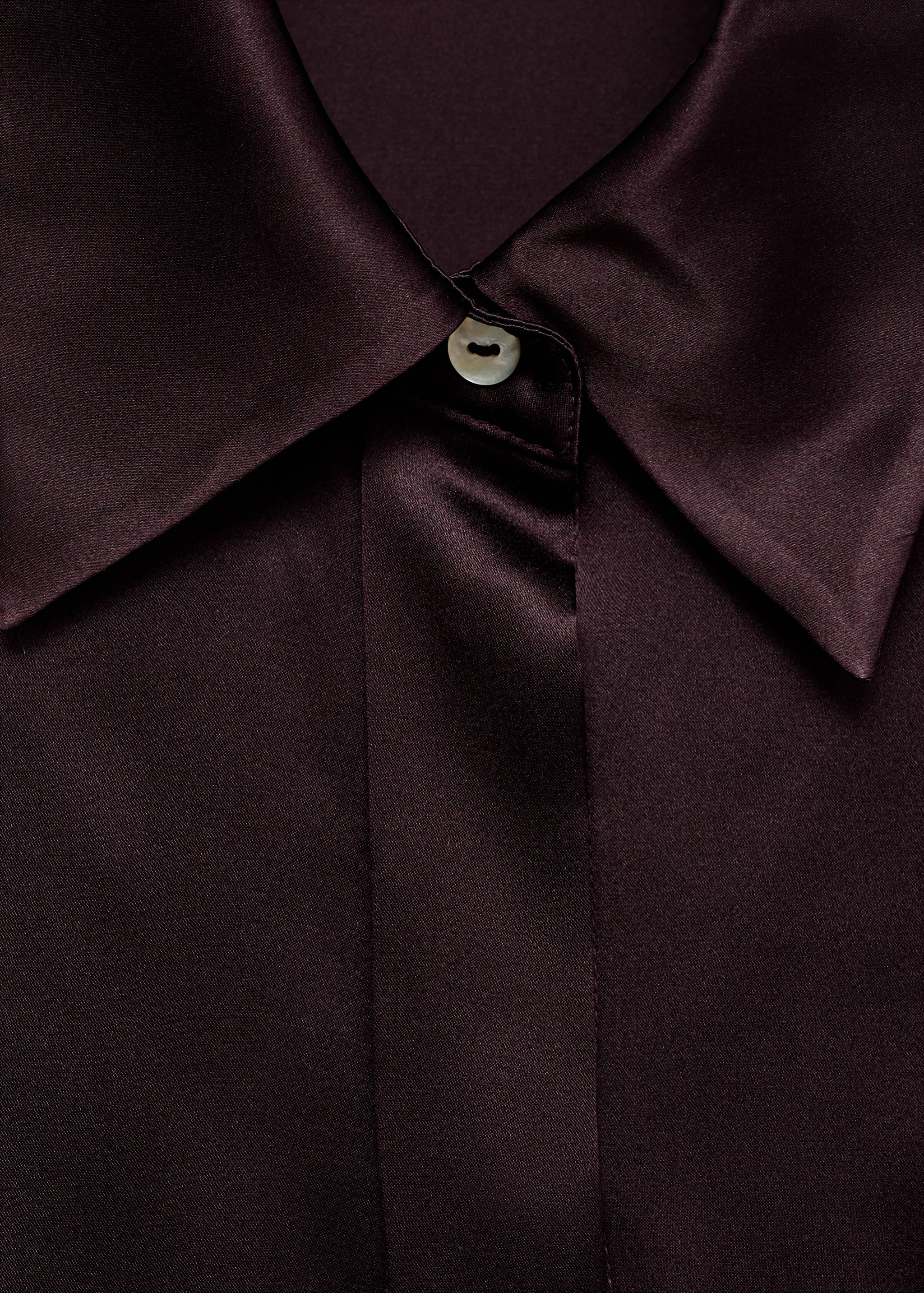 Close-up of a dark burgundy satin shirt collar and button detail.