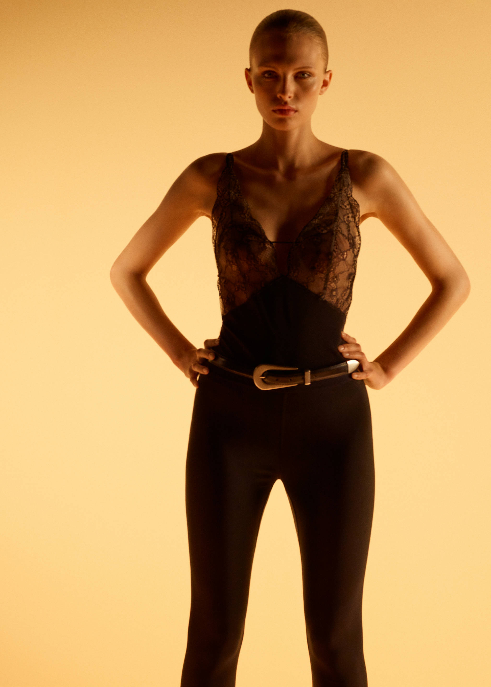 Black leggings worn with a lace bodysuit and belt.