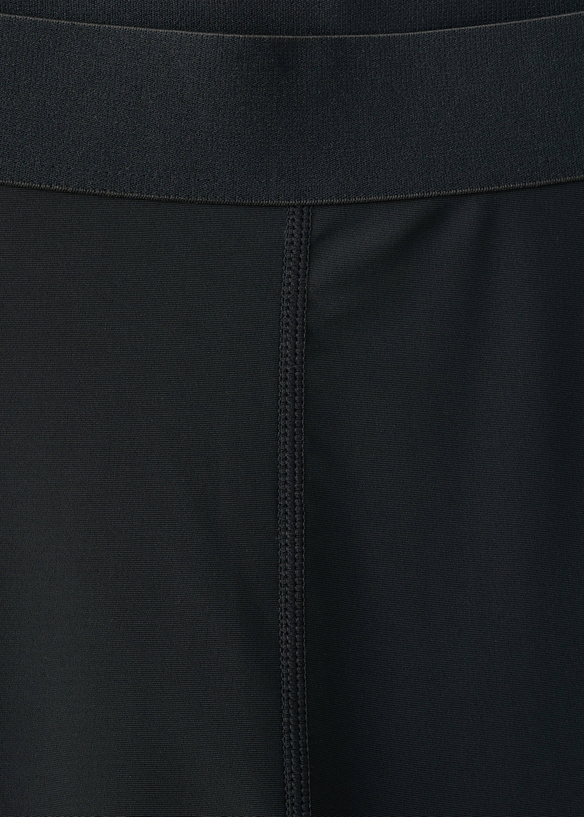 Close-up of black leggings showing the elastic waistband.