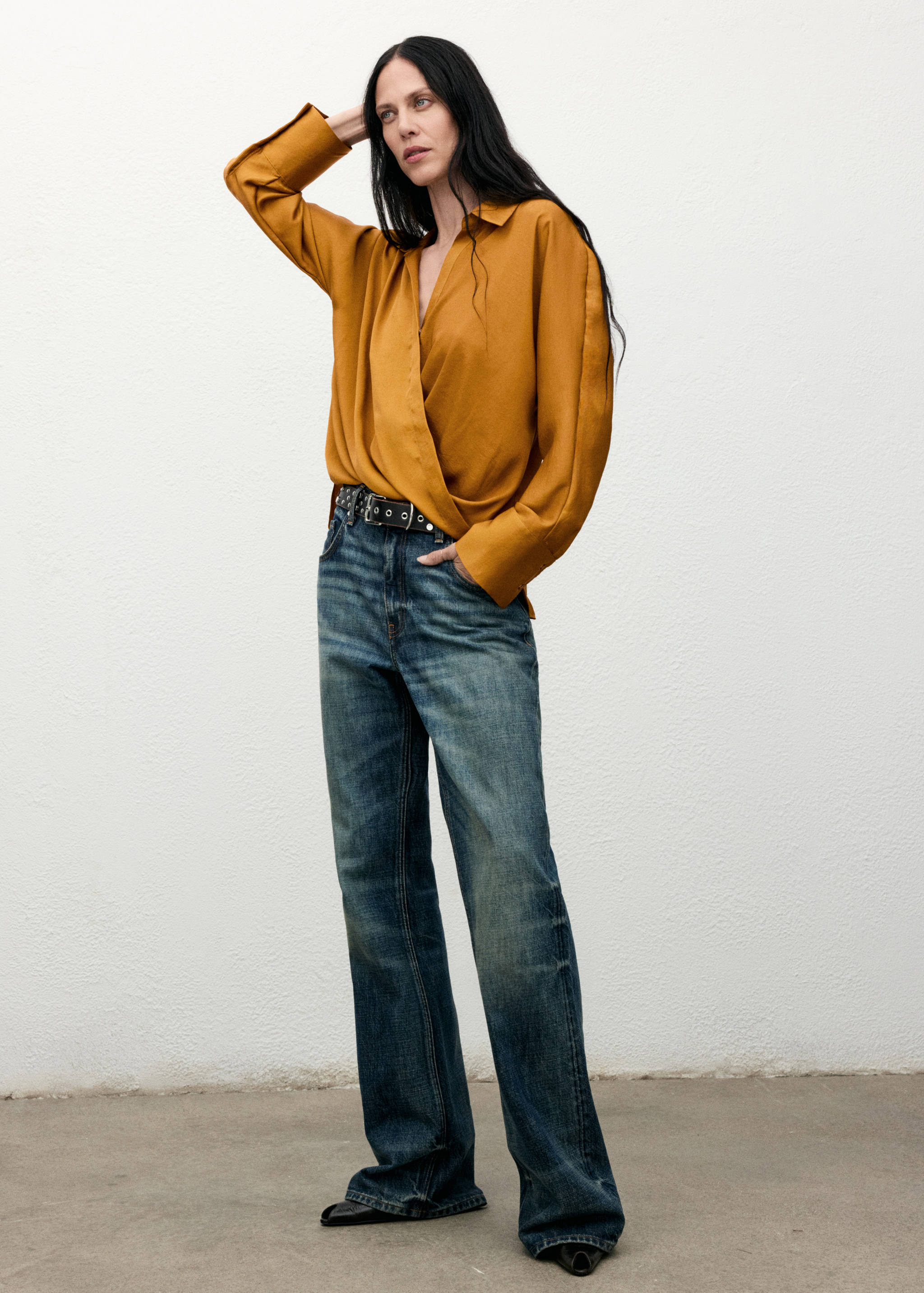 Mustard-yellow satin wrap shirt with long sleeves and a collar, worn with blue trousers.