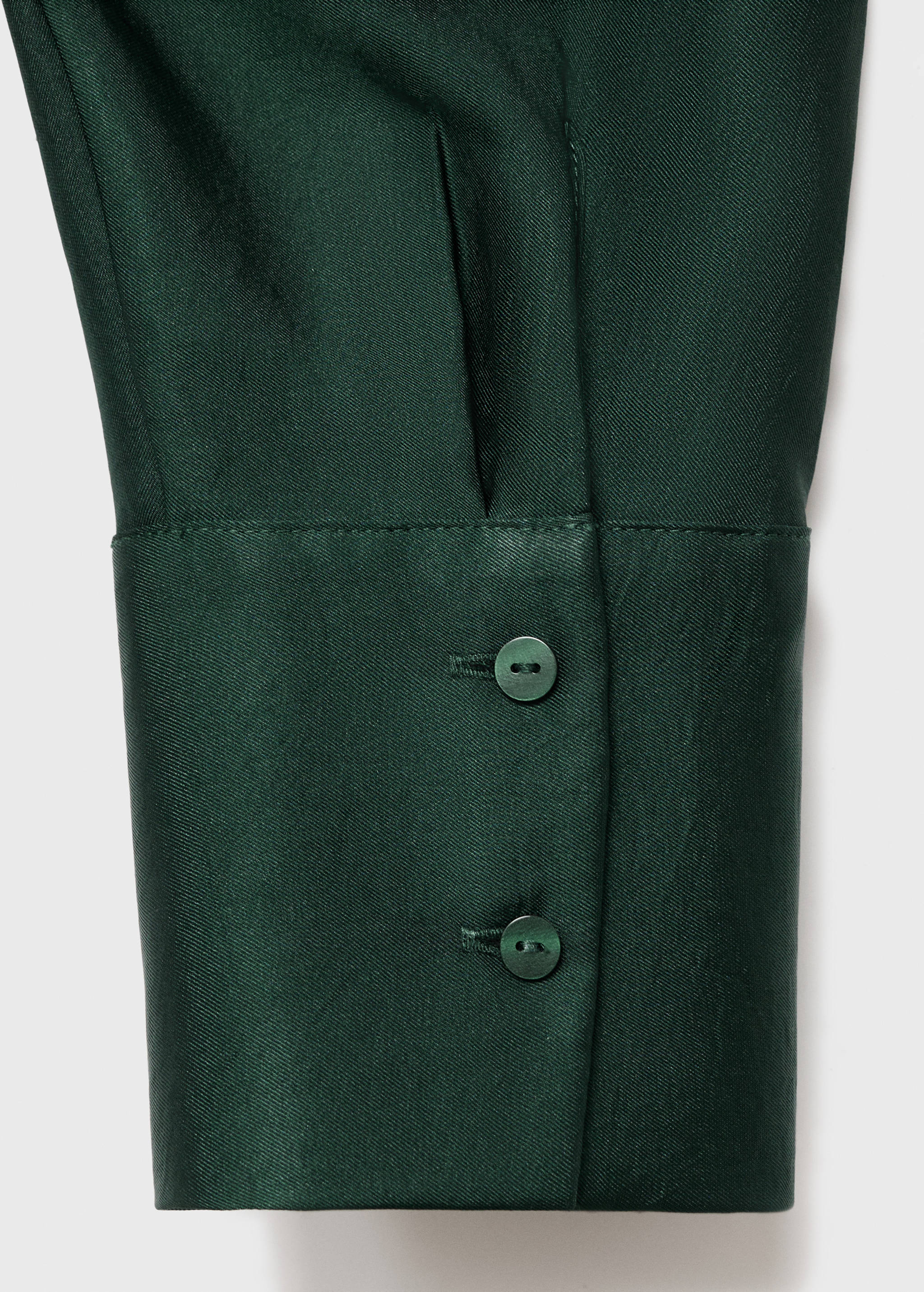 Dark green shirt cuff detail with matching buttons.