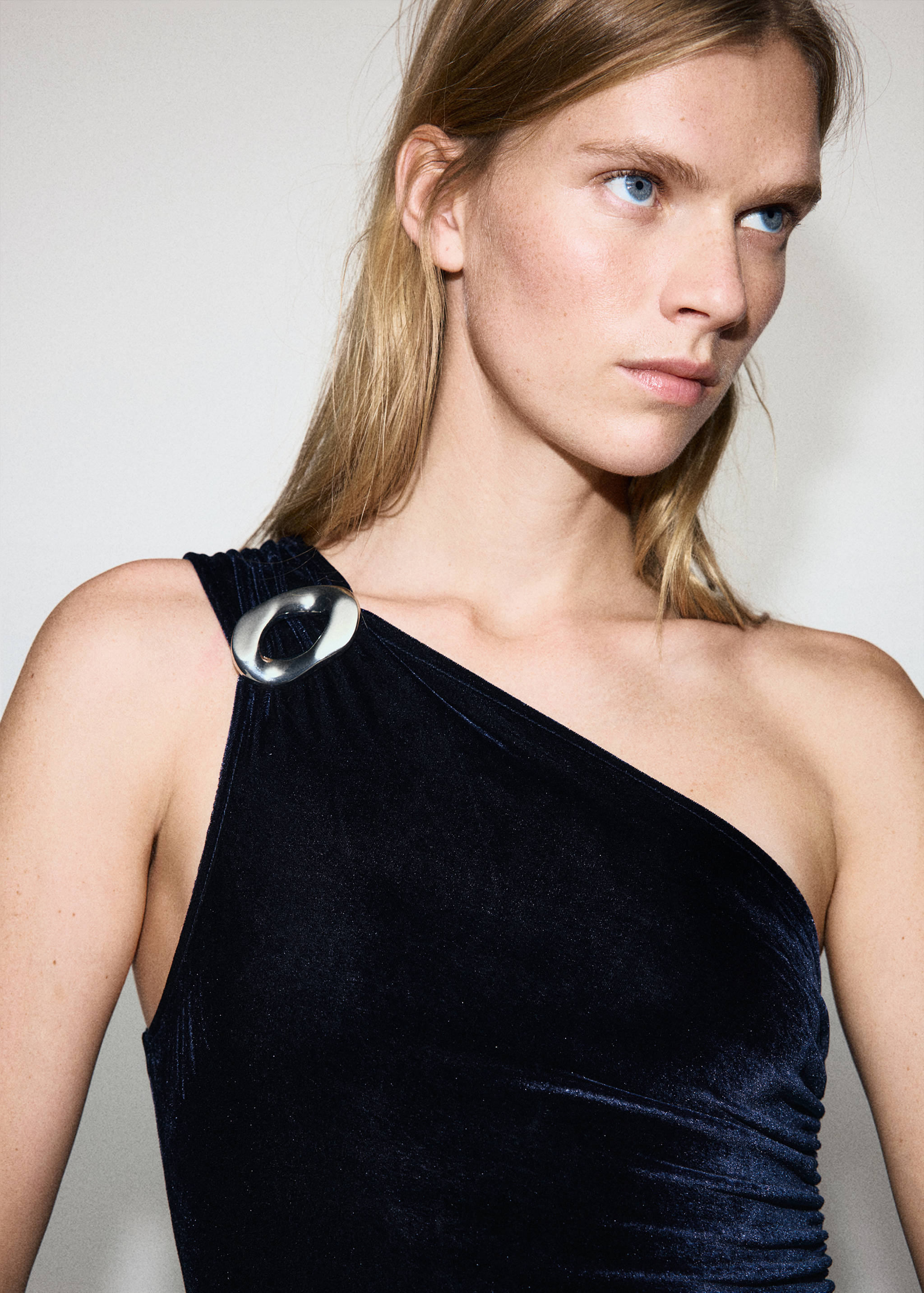 Dark blue velvet jumpsuit with an asymmetric one-shoulder strap and a silver metallic ring detail.
