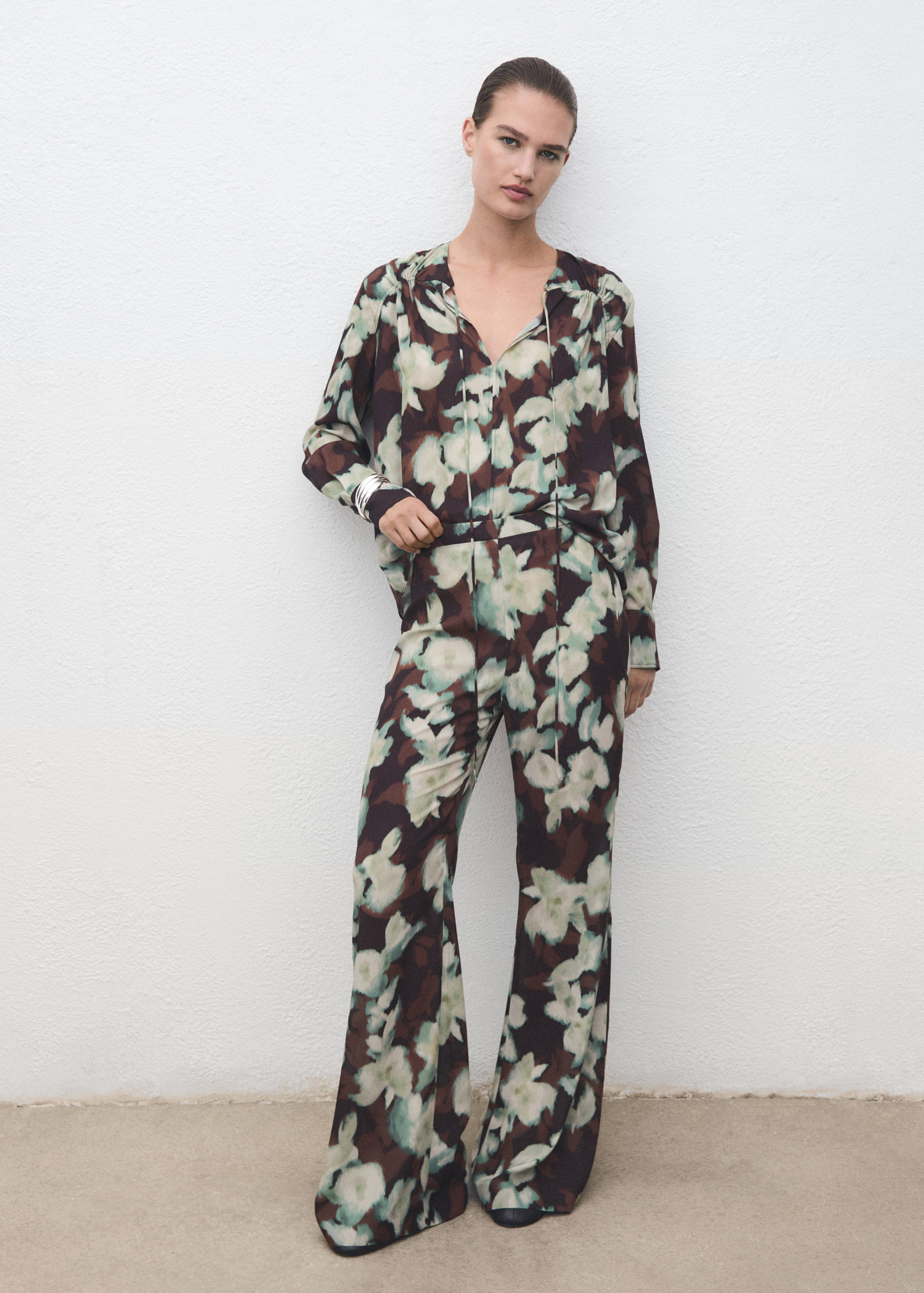 Floral print trousers in dark brown and pale green, worn with a matching long-sleeve blouse.