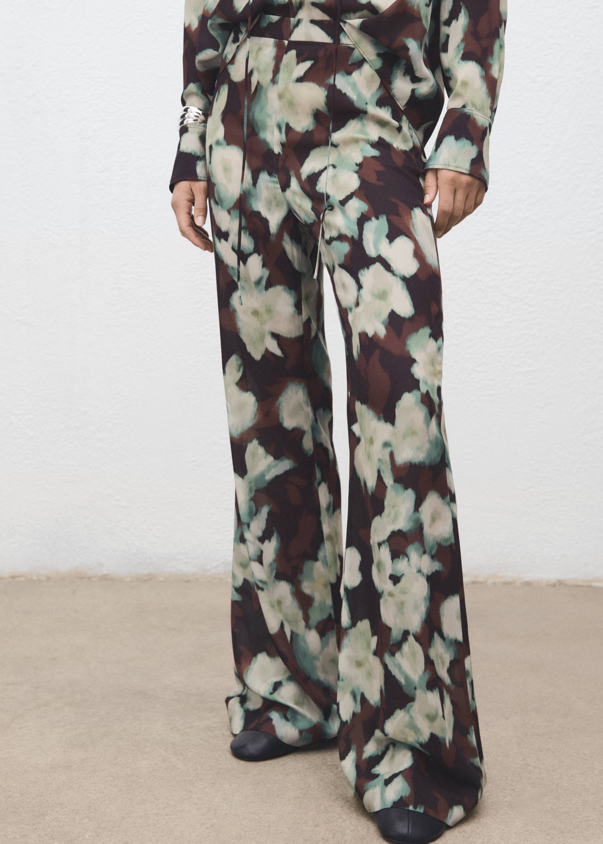 Brown floral wide-leg trousers with soft green and off-white abstract floral print.