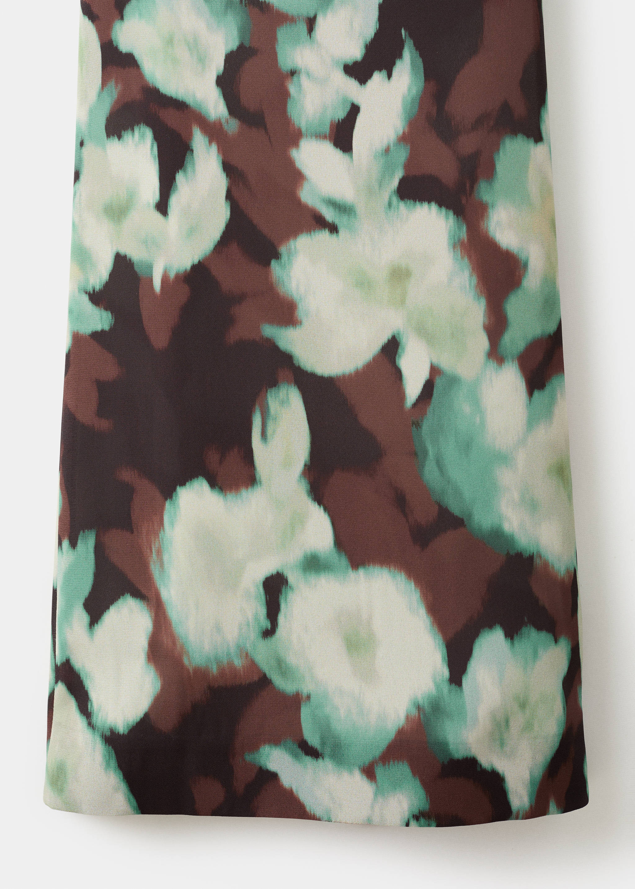 Close-up of trousers fabric with a mint green and off-white floral print on dark brown.
