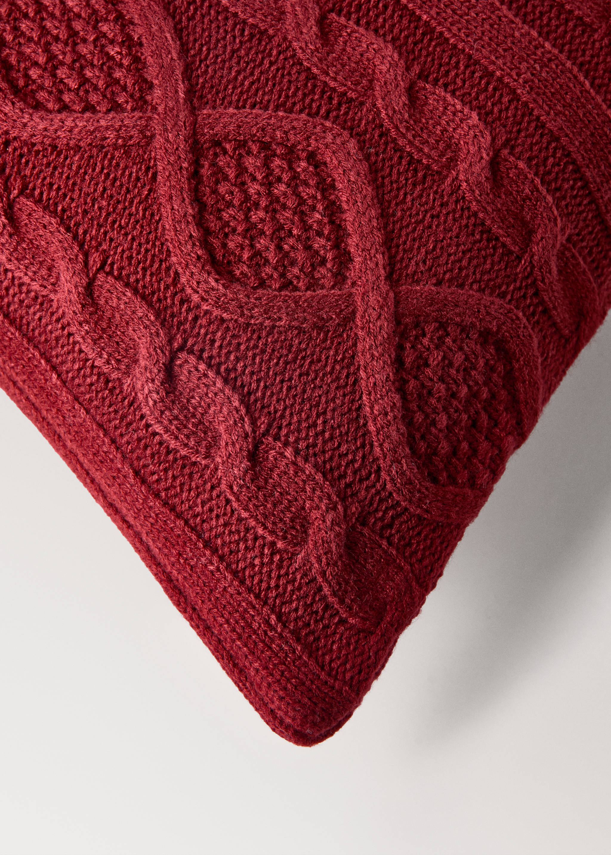 Dark red cable knit cushion cover detail.