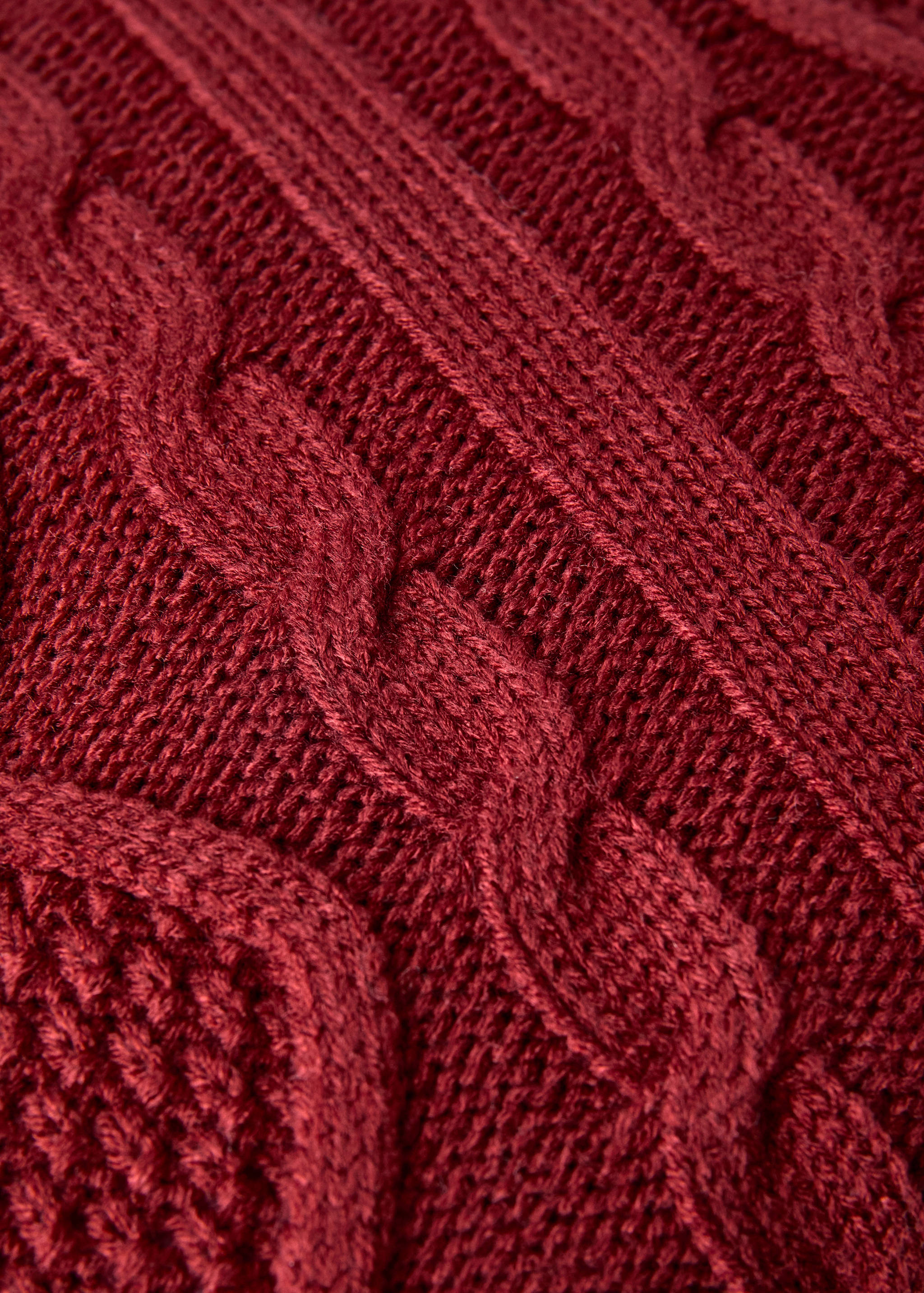 Dark red cable-knit cushion cover detail.