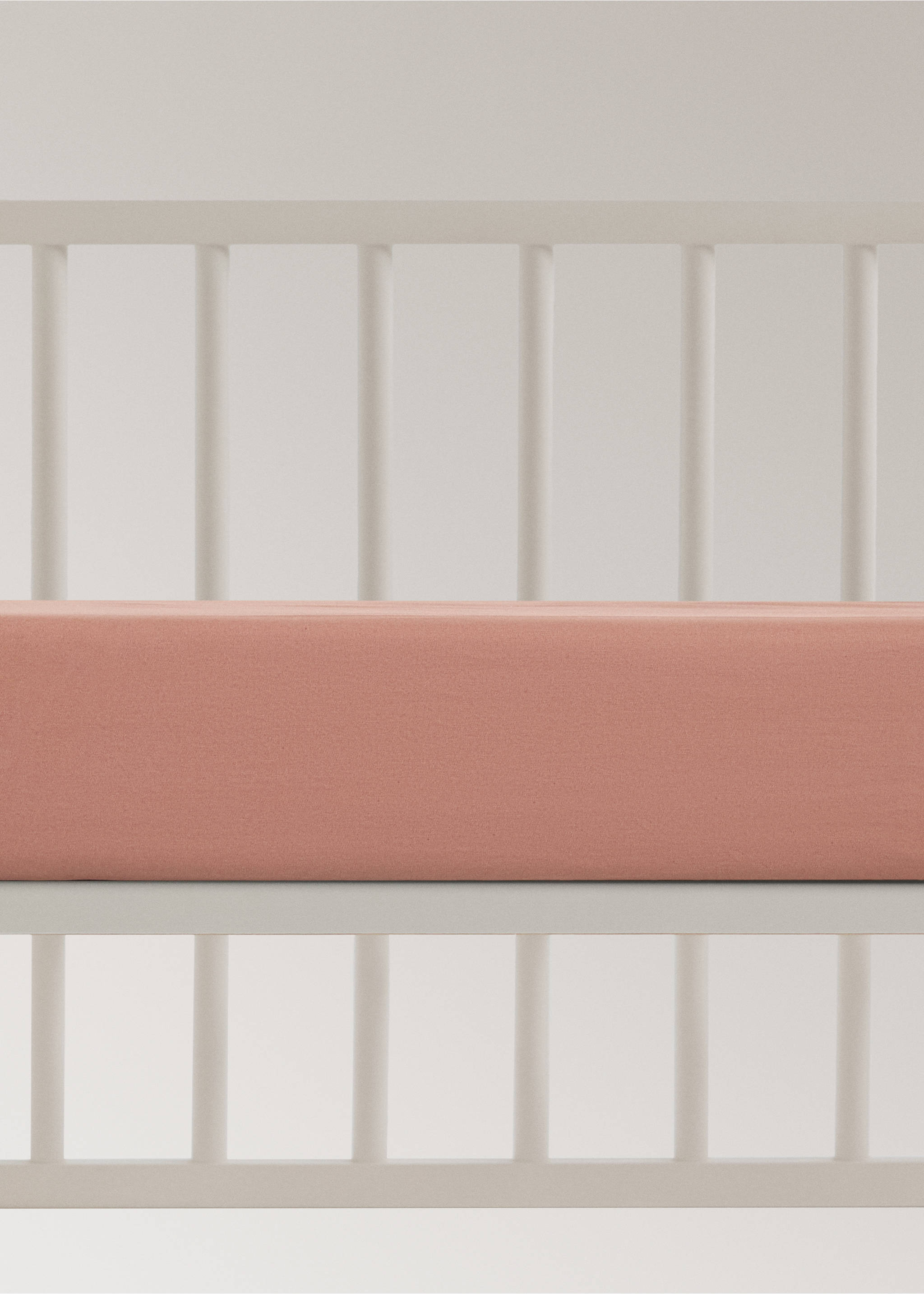 Plain pink fitted cot sheet on a white crib mattress., Brown. Ref: 17071545-00.