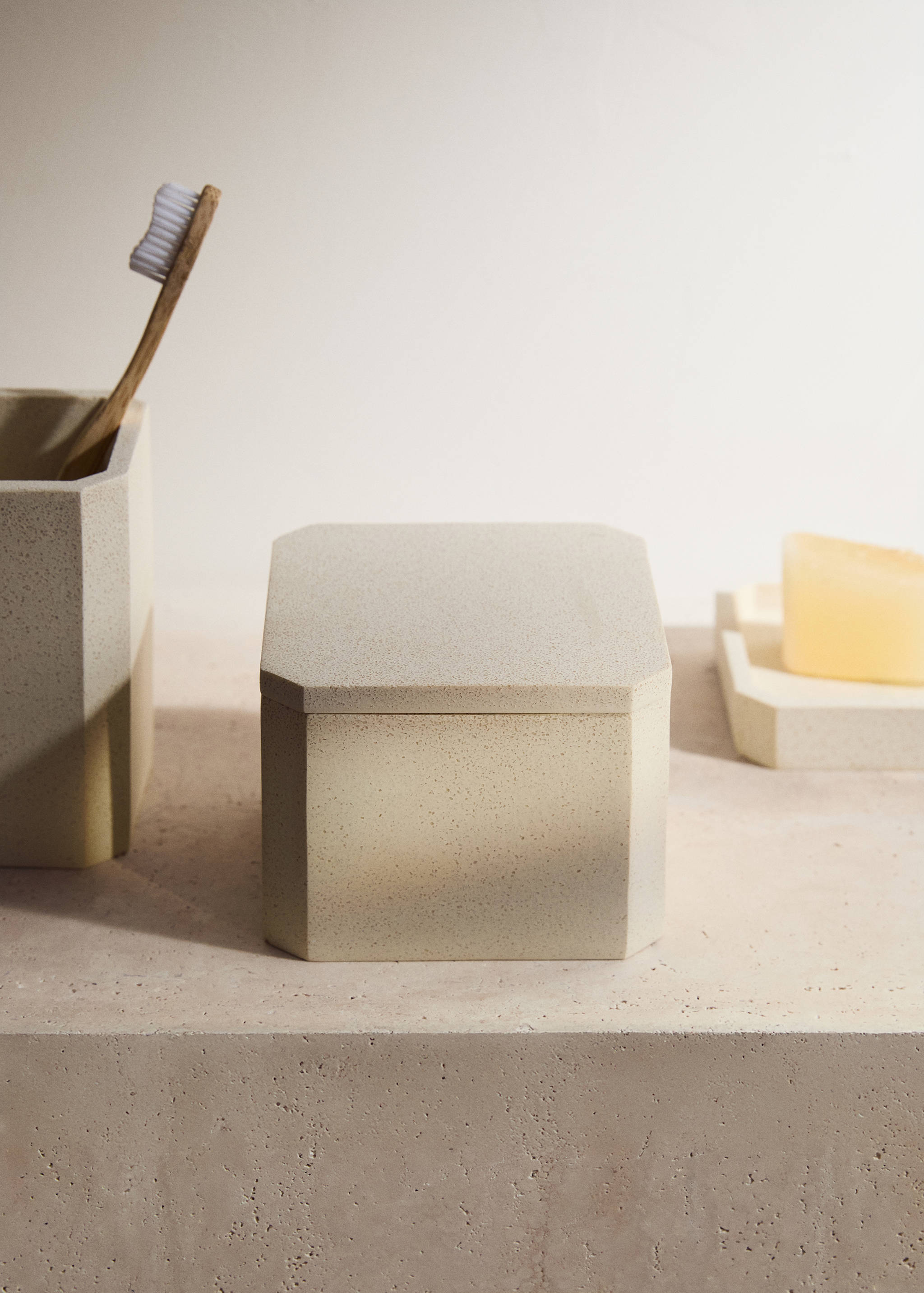 Speckled beige lidded storage box with faceted corners.
