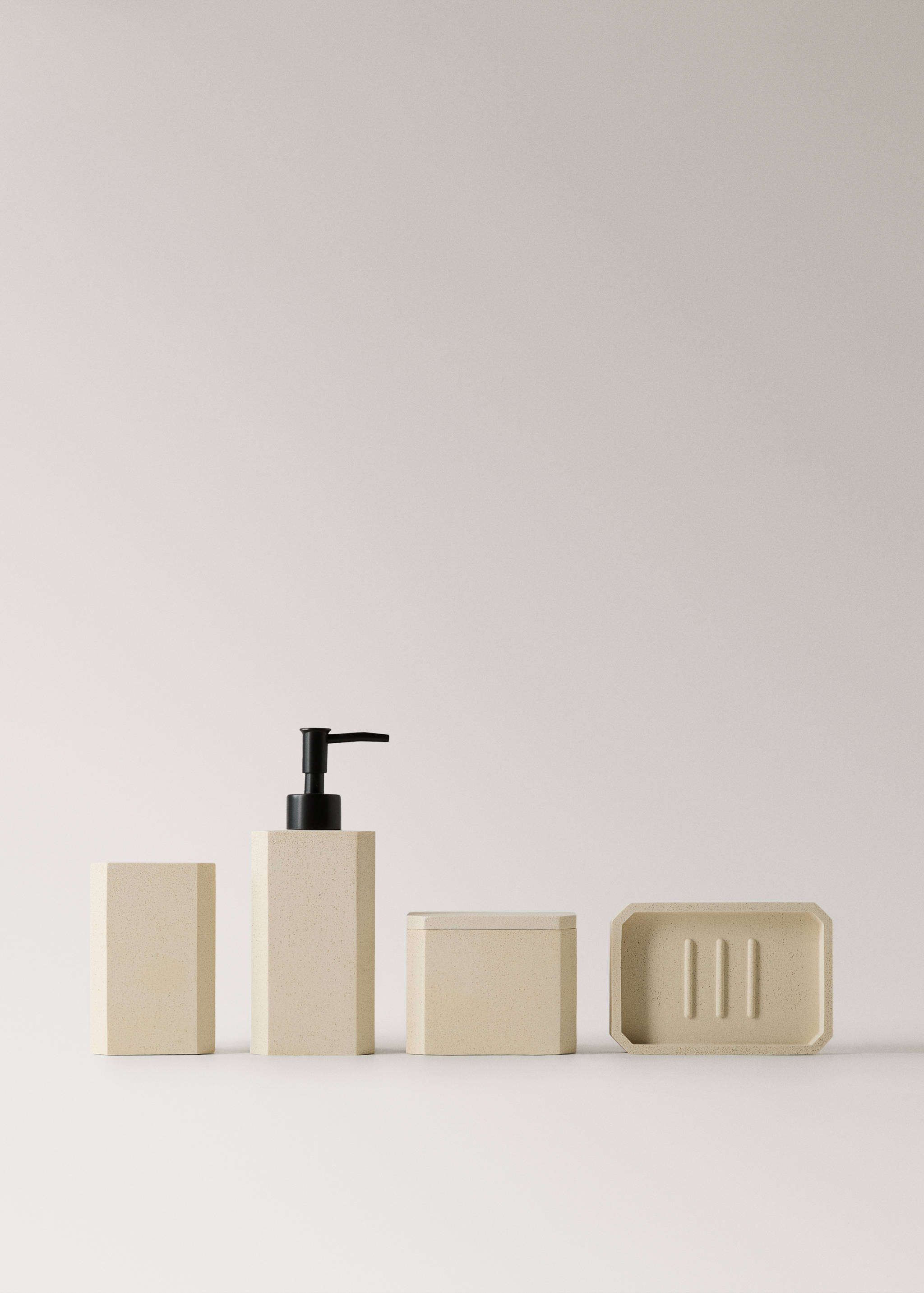 Beige speckled resin bathroom set with a soap dispenser and tray.