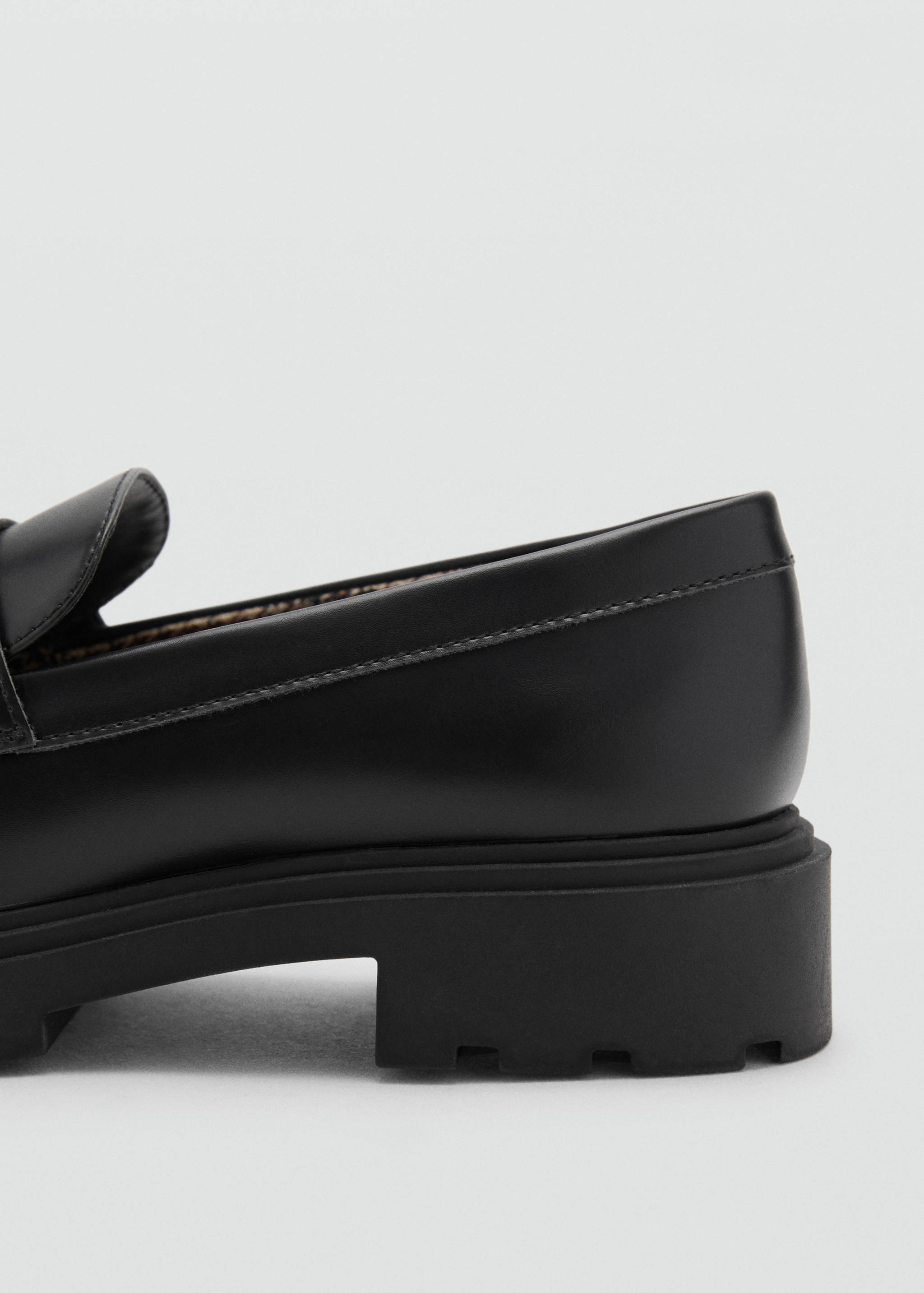 Close-up of a black loafer with a chunky lug sole.