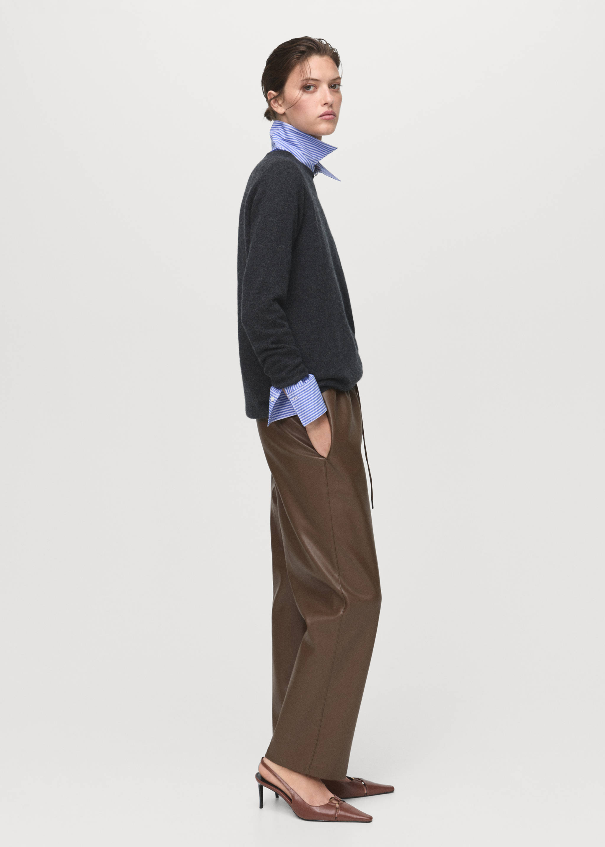 Brown faux-leather trousers worn with a grey jumper, striped shirt and heels.