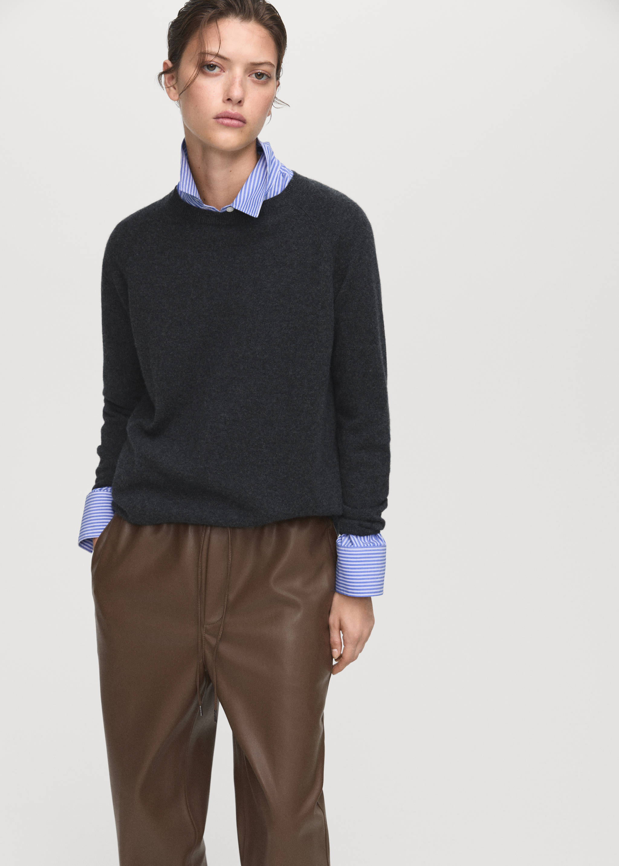 Brown faux-leather trousers with a drawstring waist, styled with a grey sweater and striped shirt.