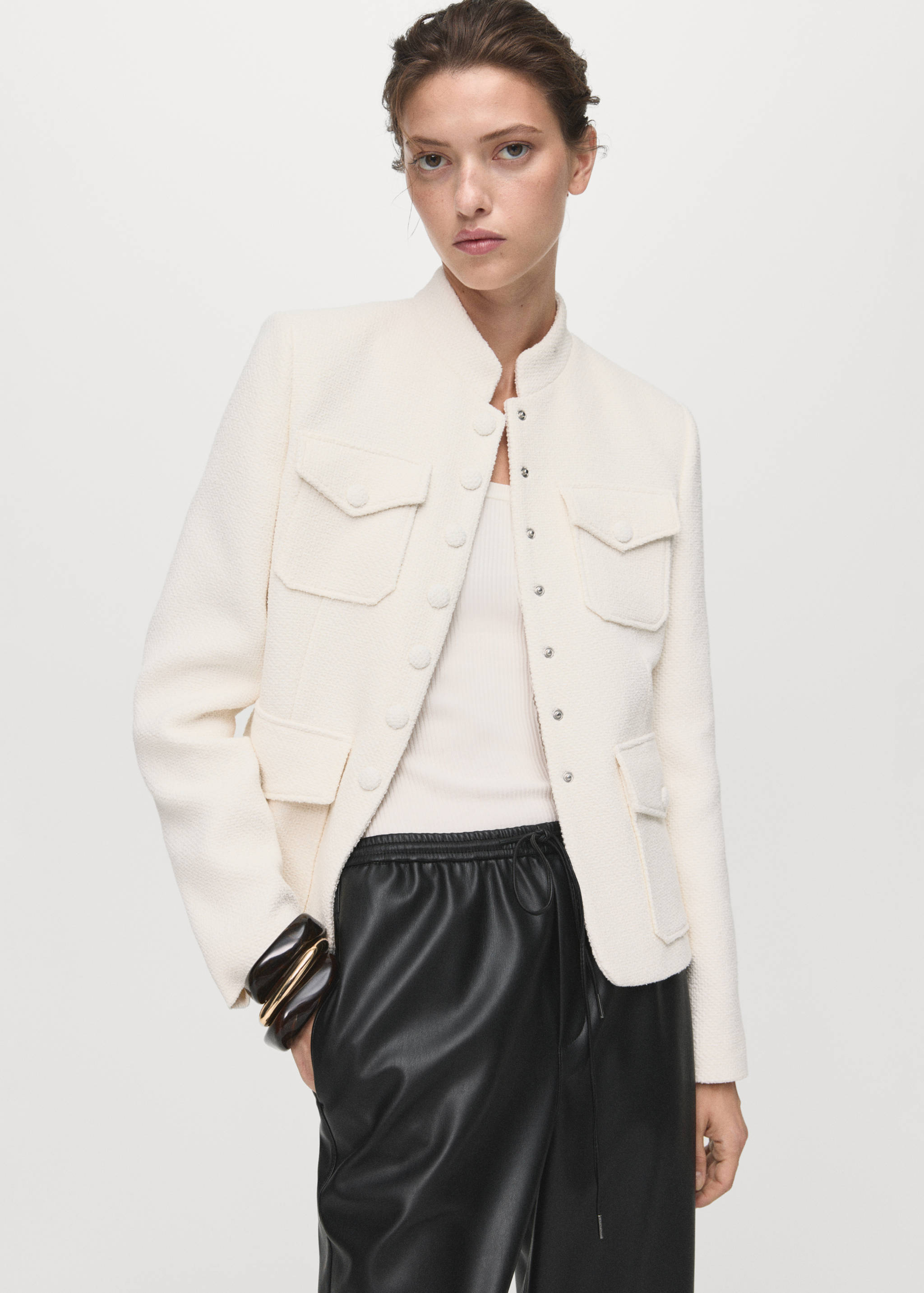 Black faux-leather trousers with an elasticated drawstring waist, worn with a textured cream jacket.