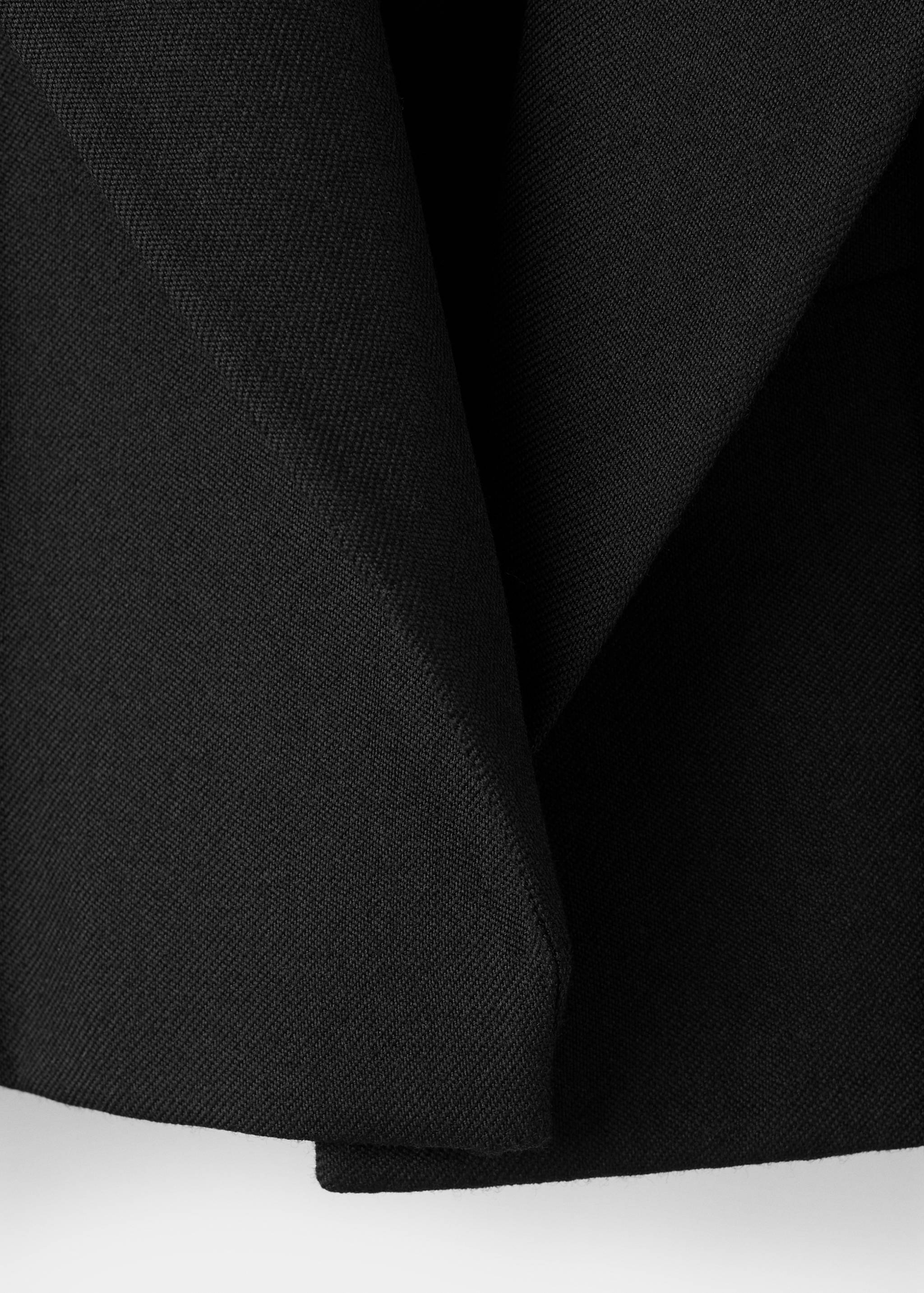 Close-up of the black fabric and lapel detail on a blazer.