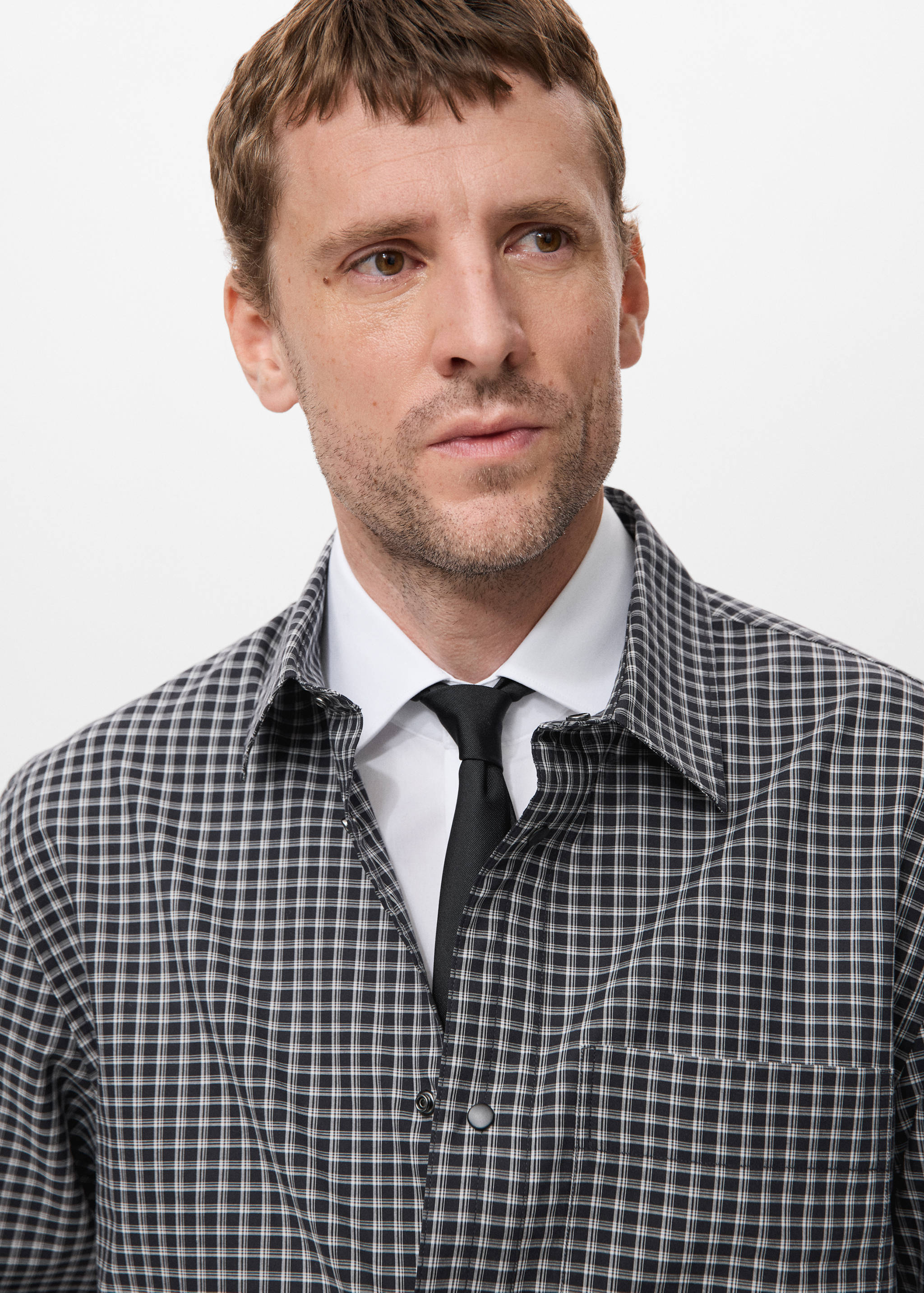 Close-up of a black, white and grey checked shirt with a black tie.