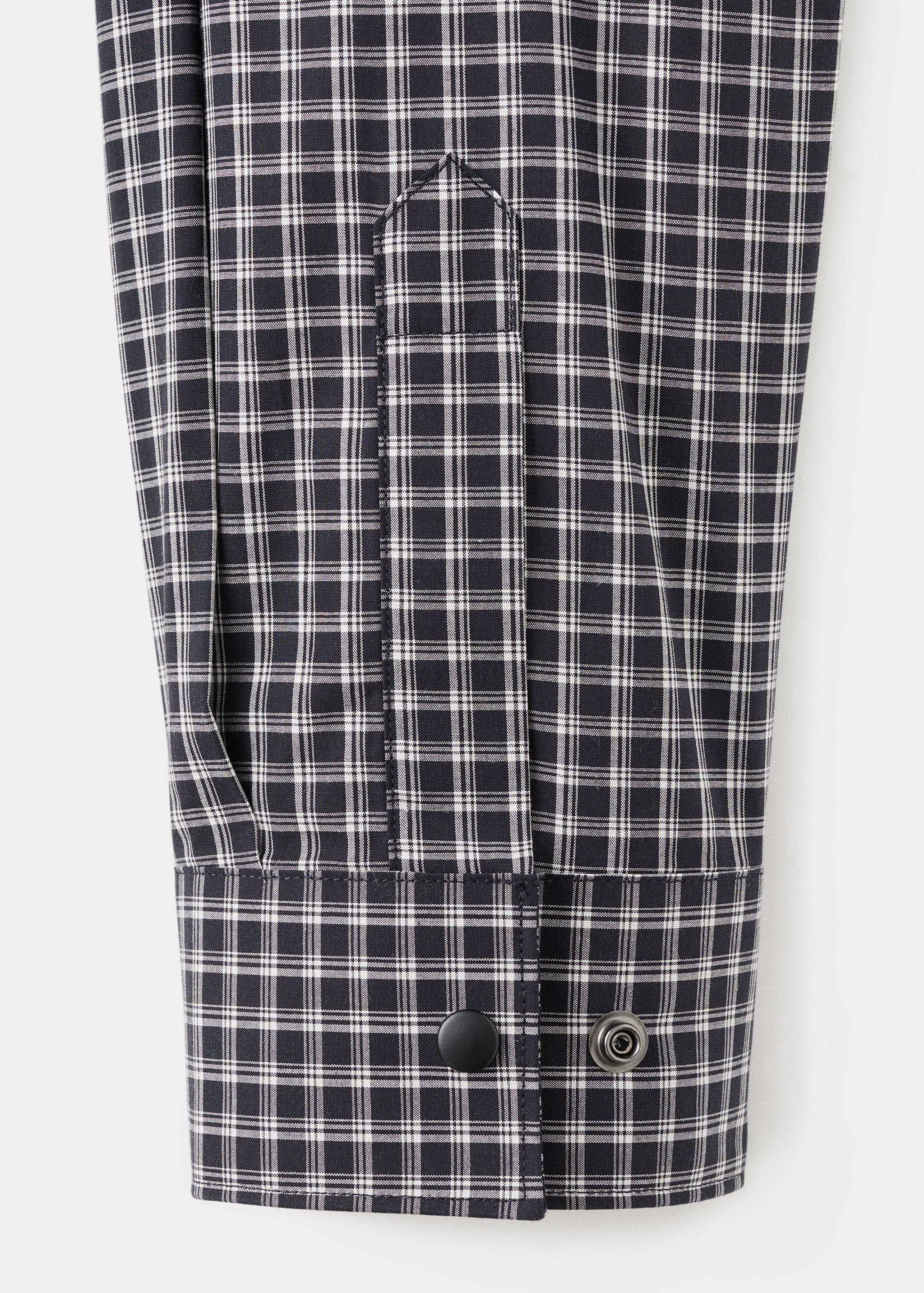 Close-up of a black and white checkered shirt cuff with snap buttons.