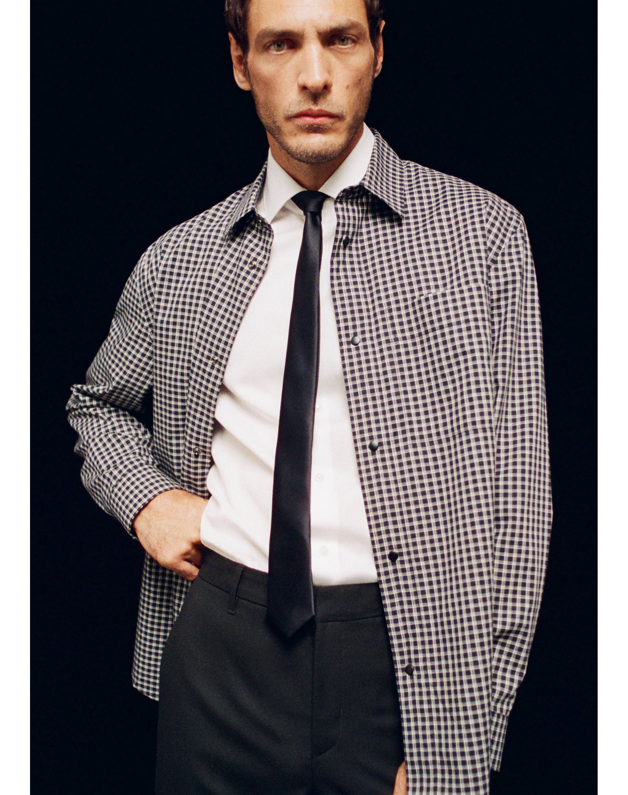 Black-and-white checkered shirt worn over a white shirt and tie.