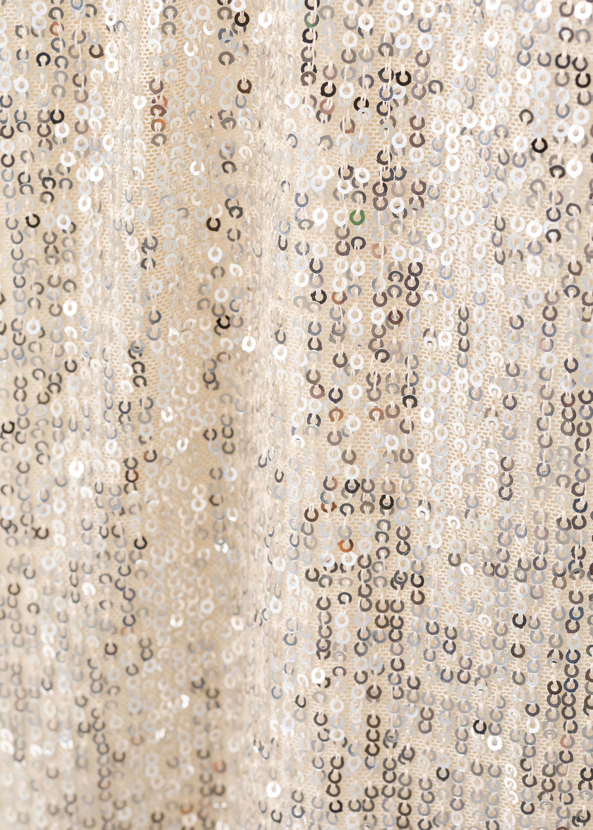 Close-up of a sequinned dress fabric with silver sequins on mesh.
