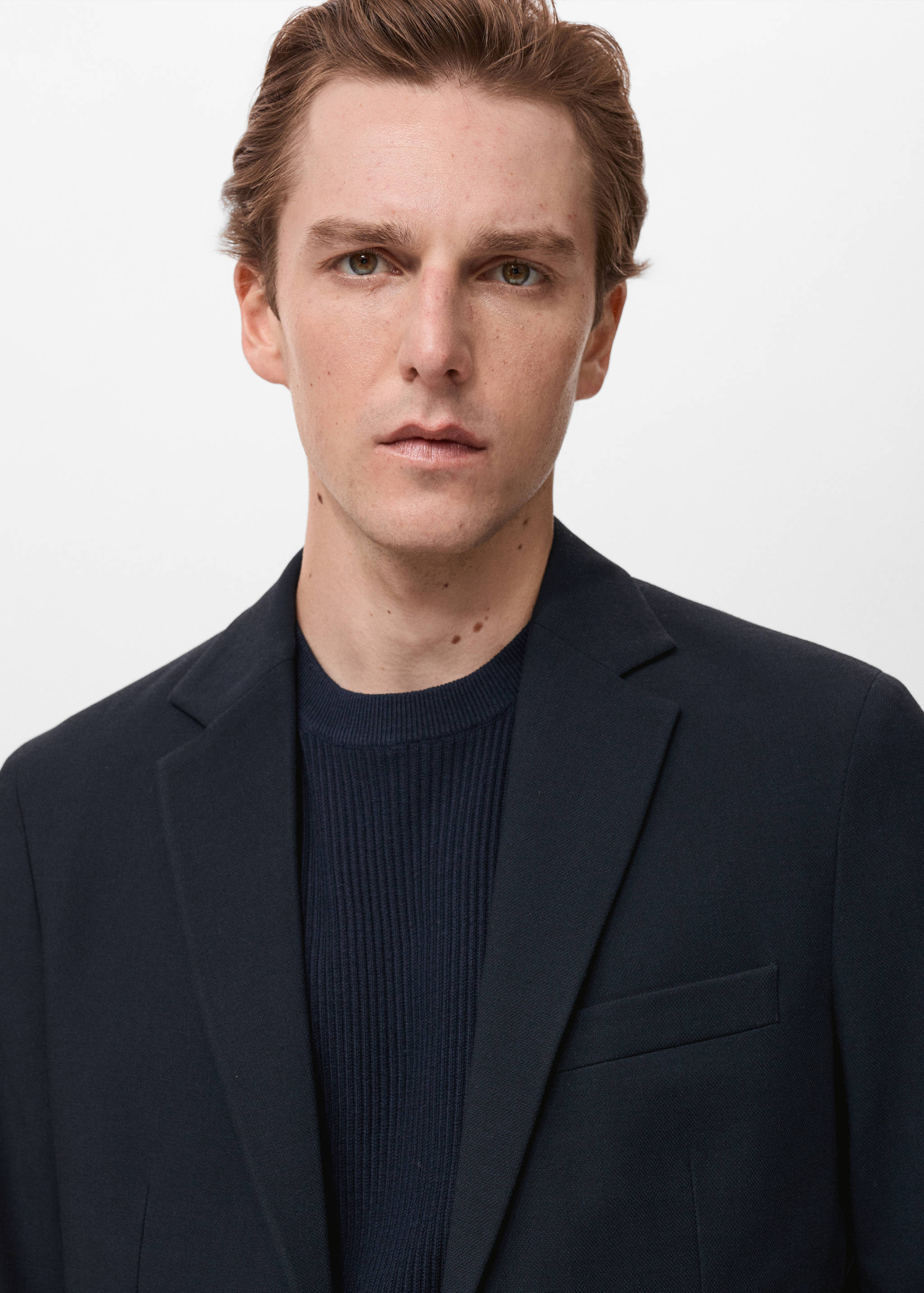 Close-up of a navy blue blazer with notched lapels and a chest pocket.