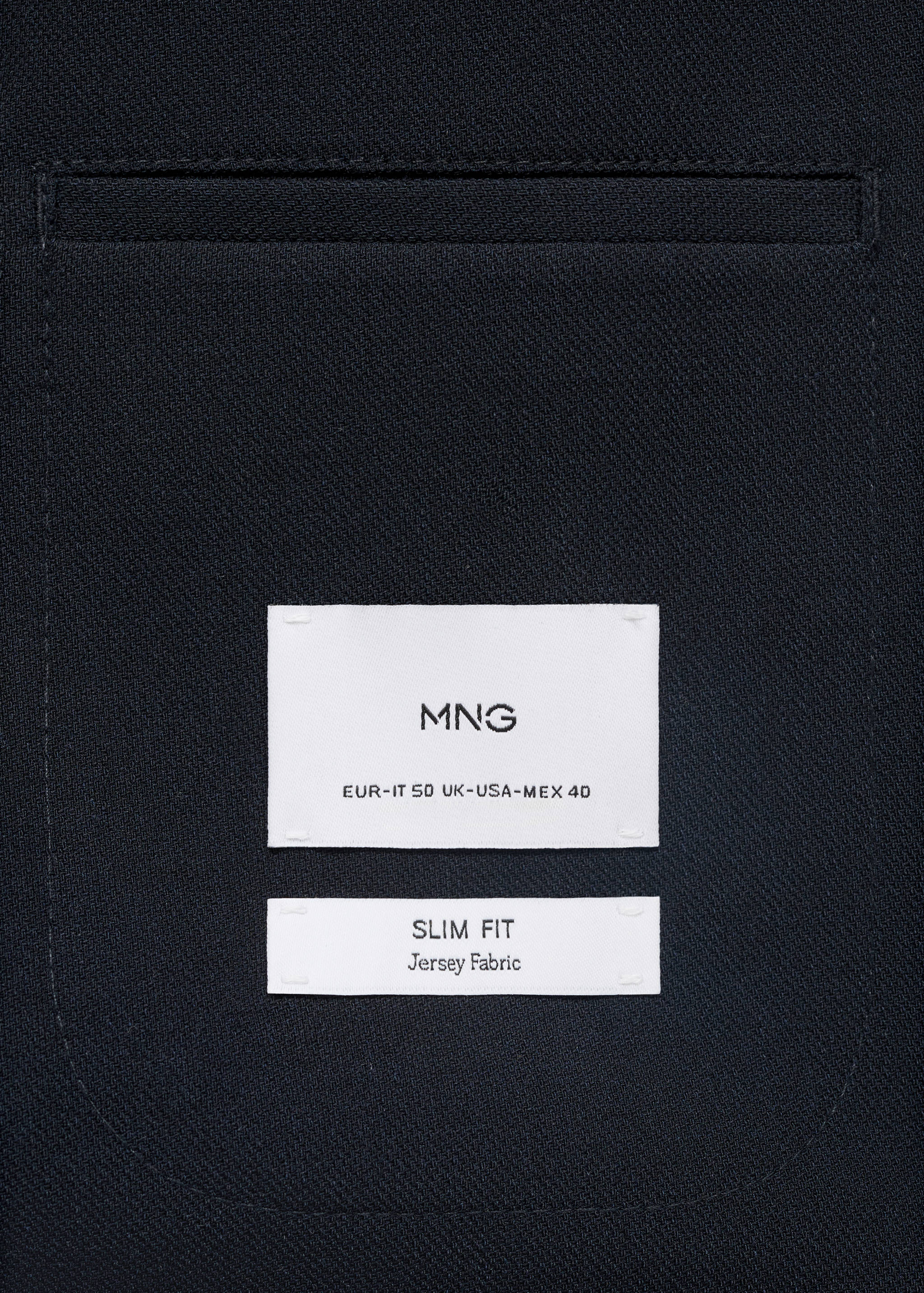Close-up of the jersey fabric and pocket detail of a slim fit navy blue blazer.