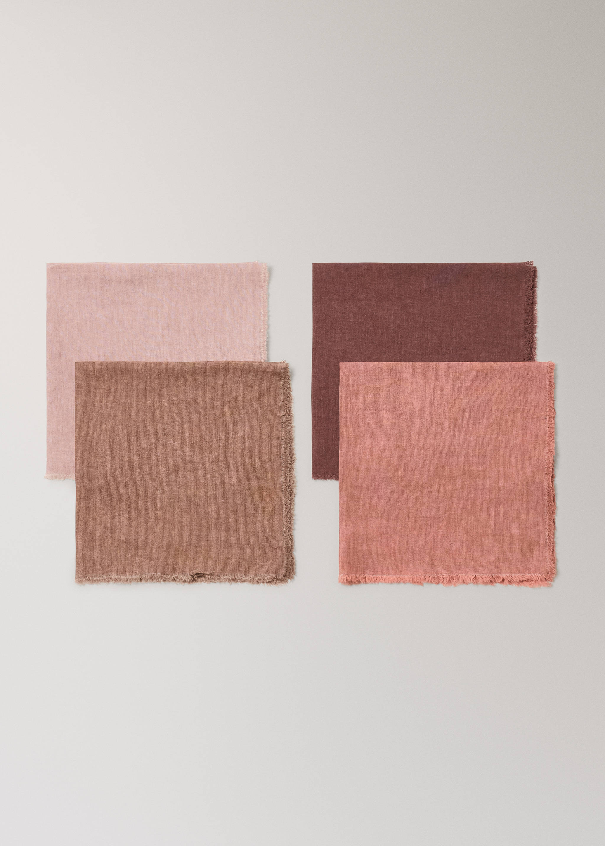 Set of four woven fabric napkins in pink and brown with frayed edges.